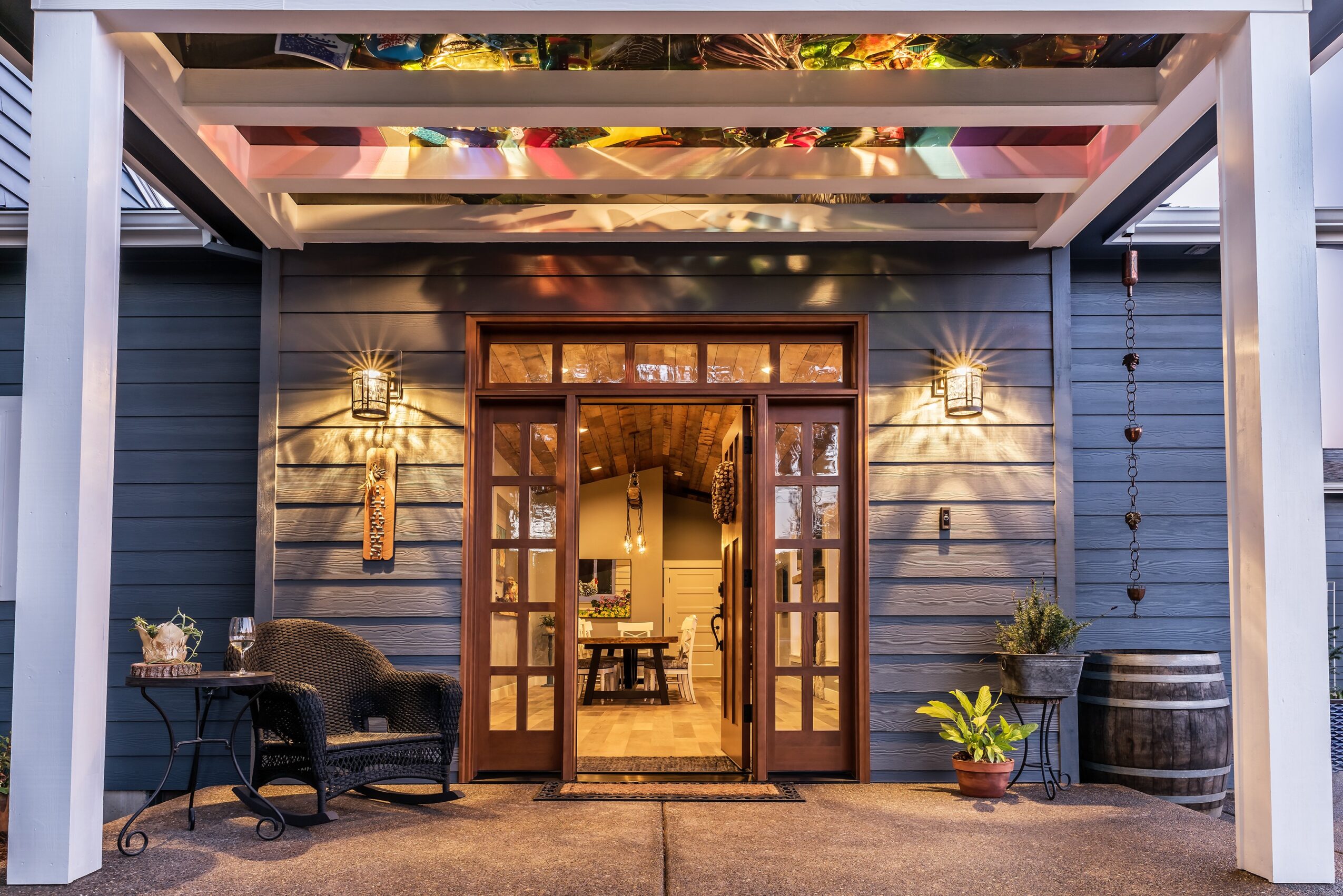 Open doorway leading into a cozy interior, with outdoor seating and decorative lighting, under a colorful awning.