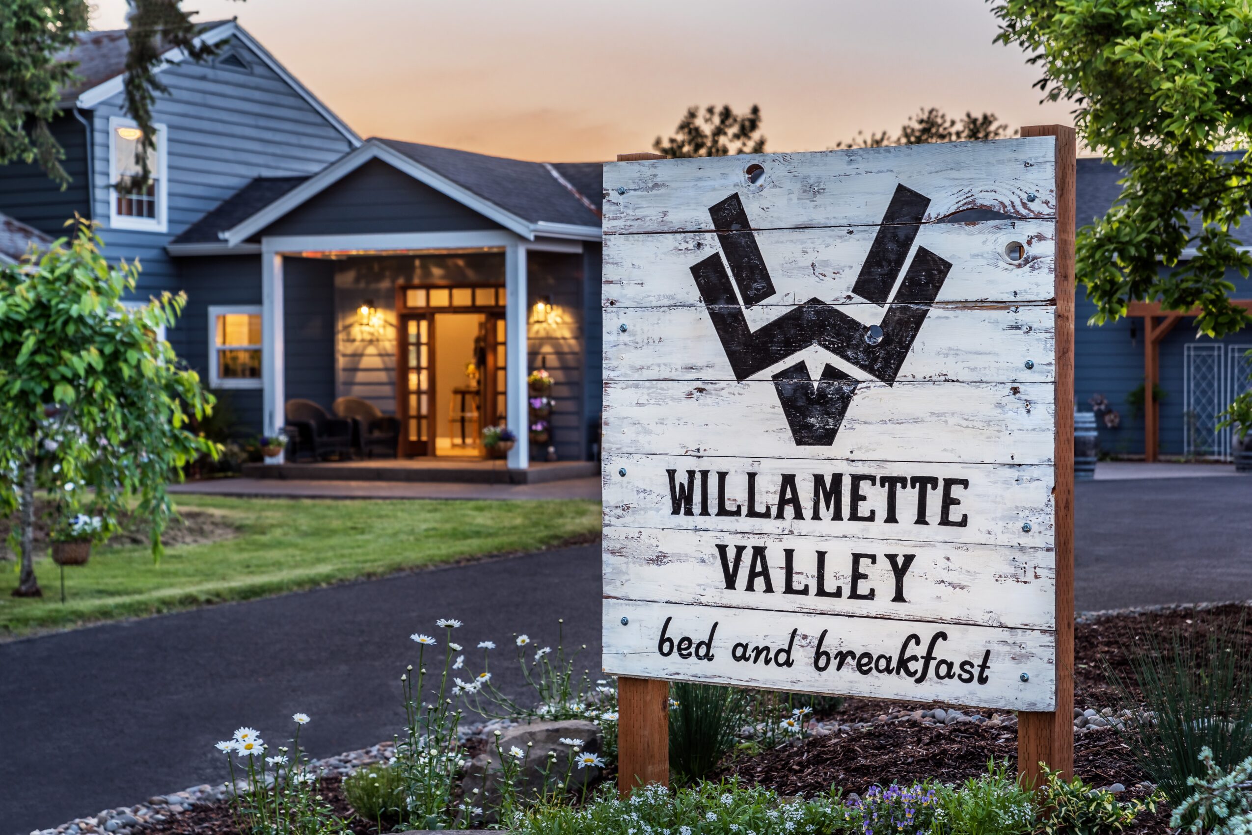 Signboard for Willamette Valley bed and breakfast in front of a house with trees and a driveway.