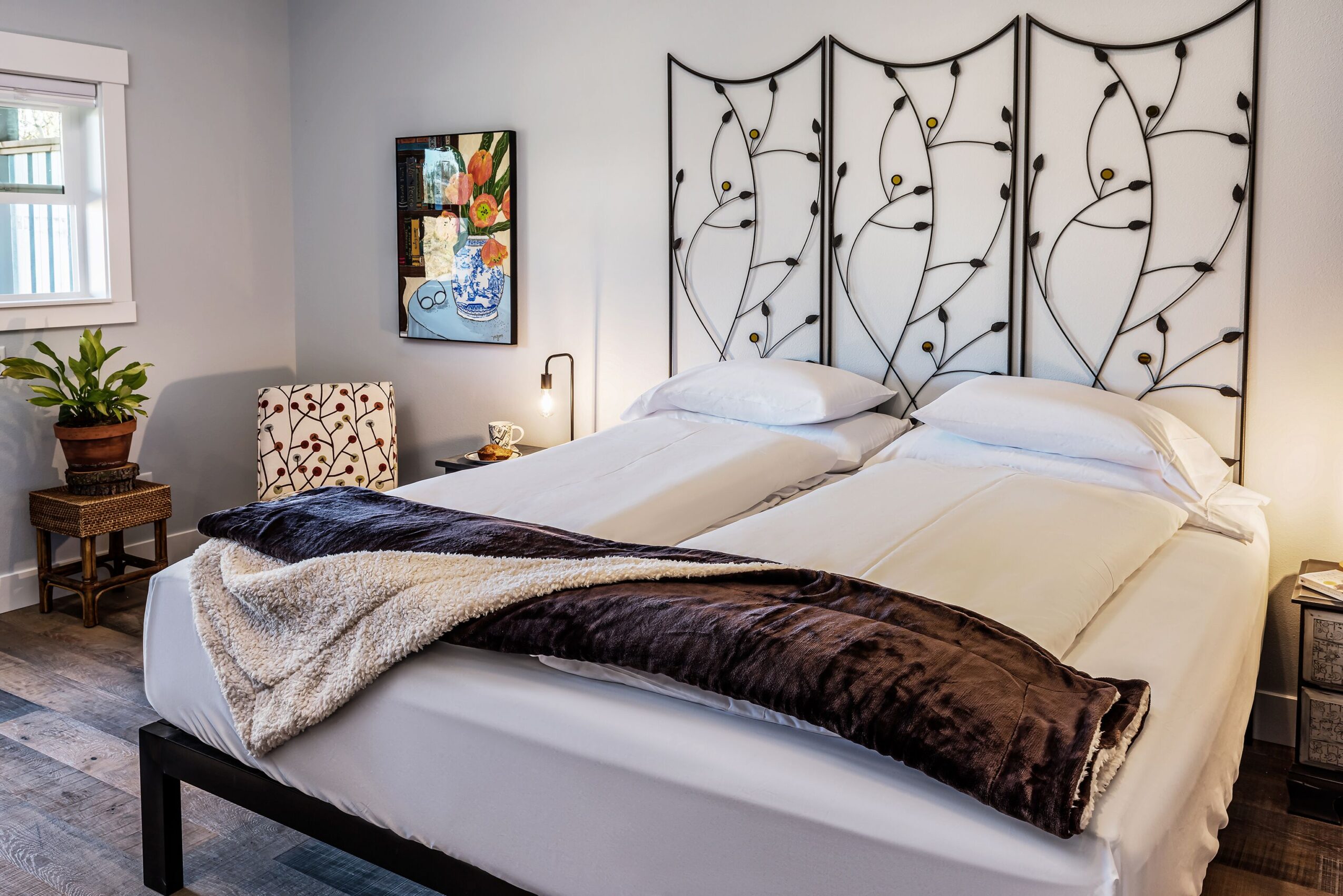 Bedroom with a bed, decorative headboard, side table, chair, and artwork on the wall.