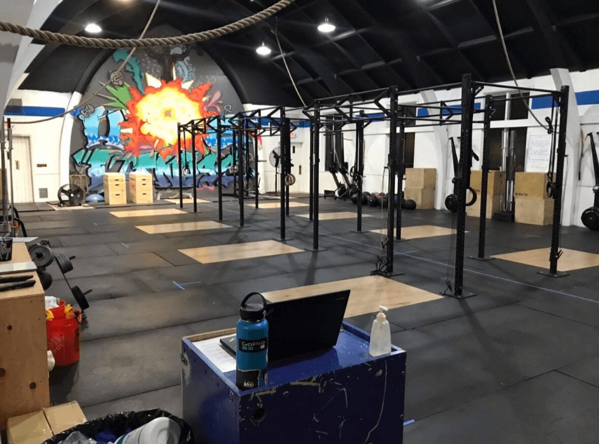 Gym with black metal racks, wooden boxes, and a colorful comic-style mural on the wall.