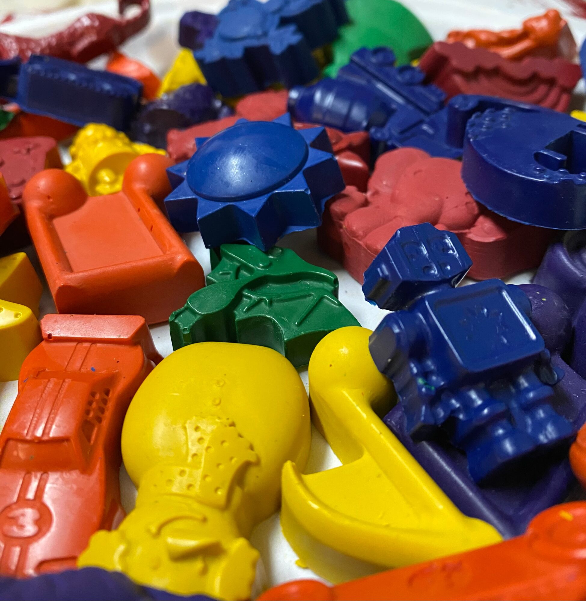 Colorful plastic toy blocks and shapes scattered together, including yellow, blue, green, red, and orange pieces.
