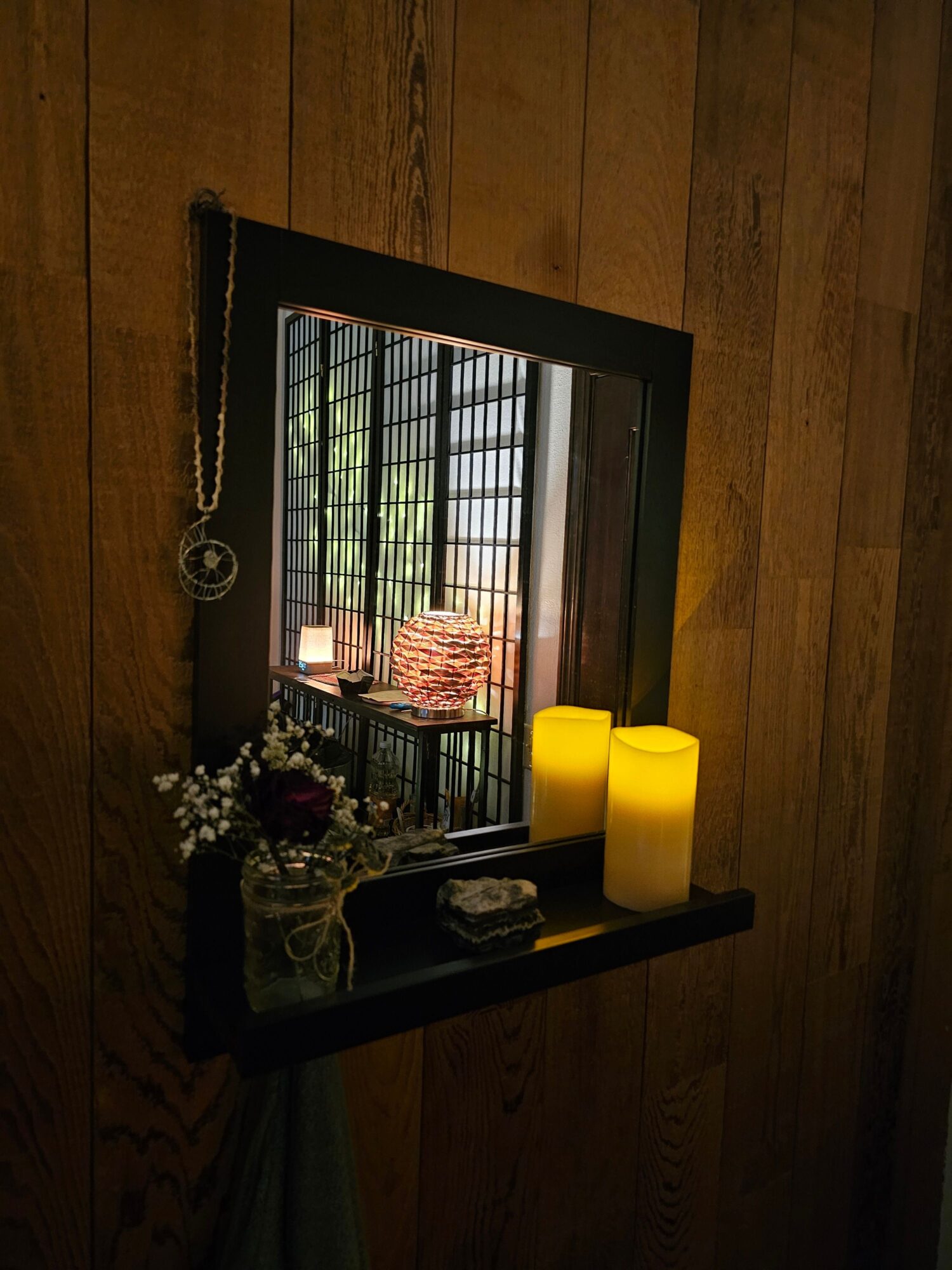 Mirror reflecting a room with window, yellow object, and decorative items on a black tray, on wooden floor.