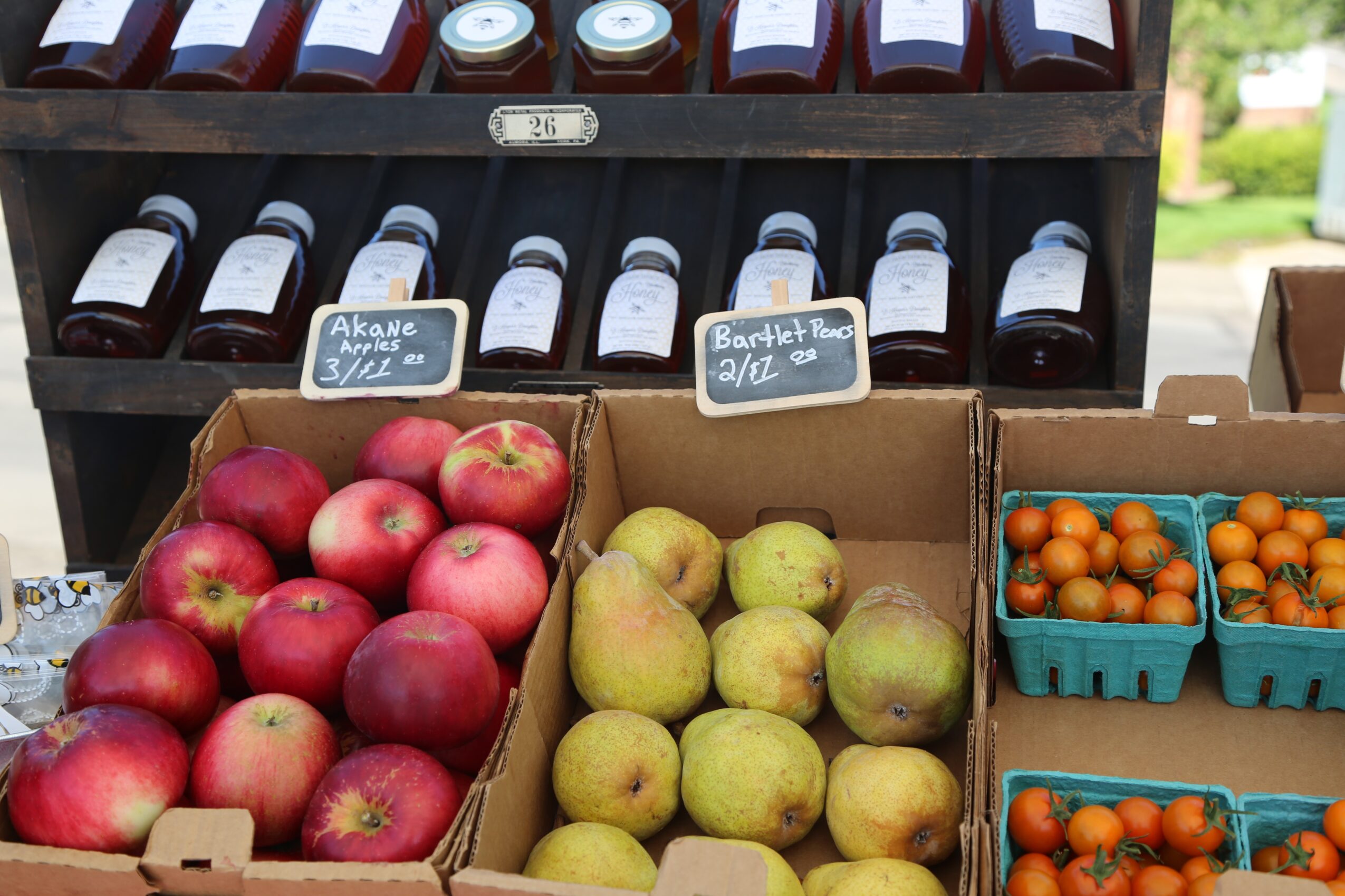 Display of apples, pears, and small orange fruits in baskets at a market stall.