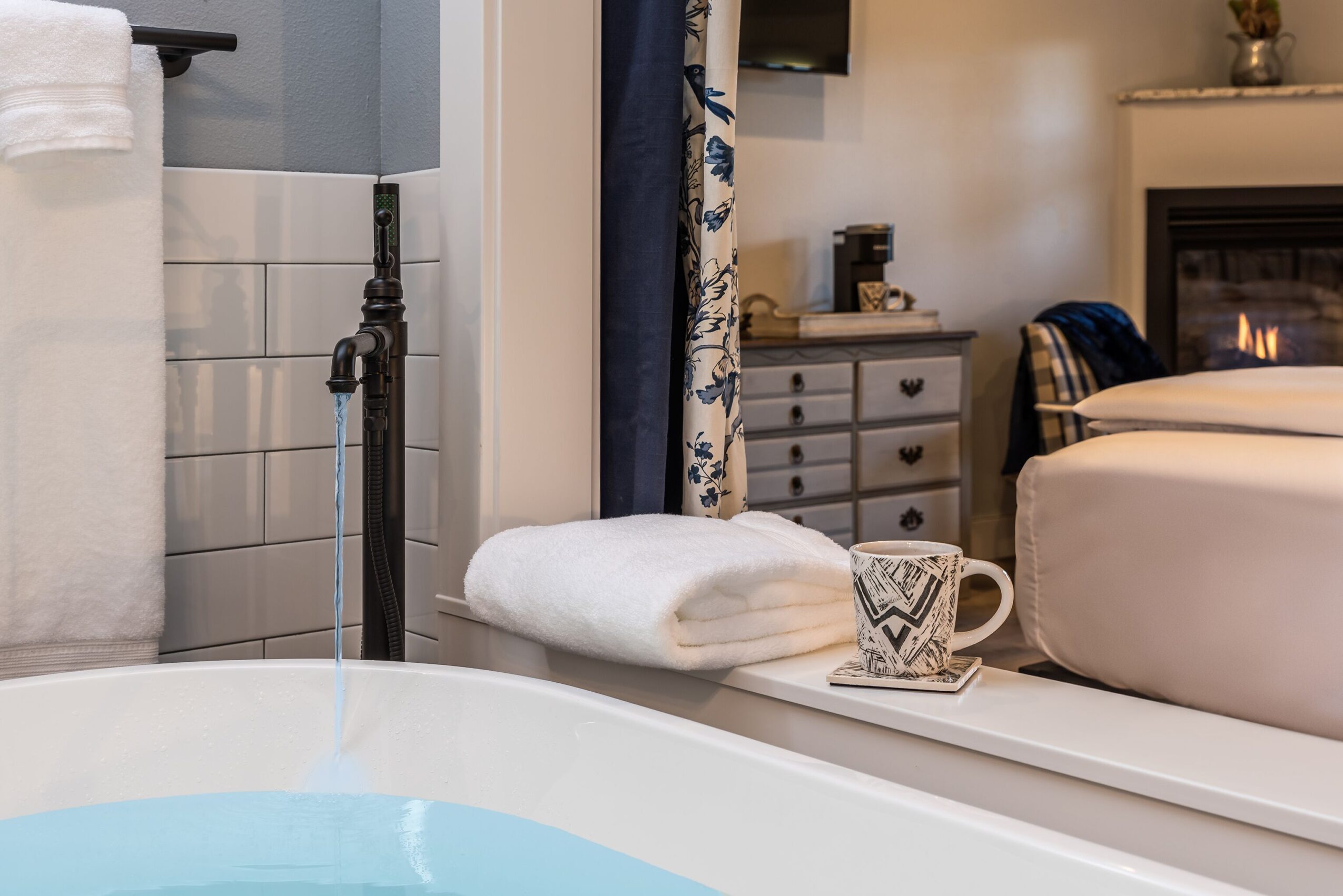 Bathroom with towel, cup, and bed visible in the background, cozy room setting.