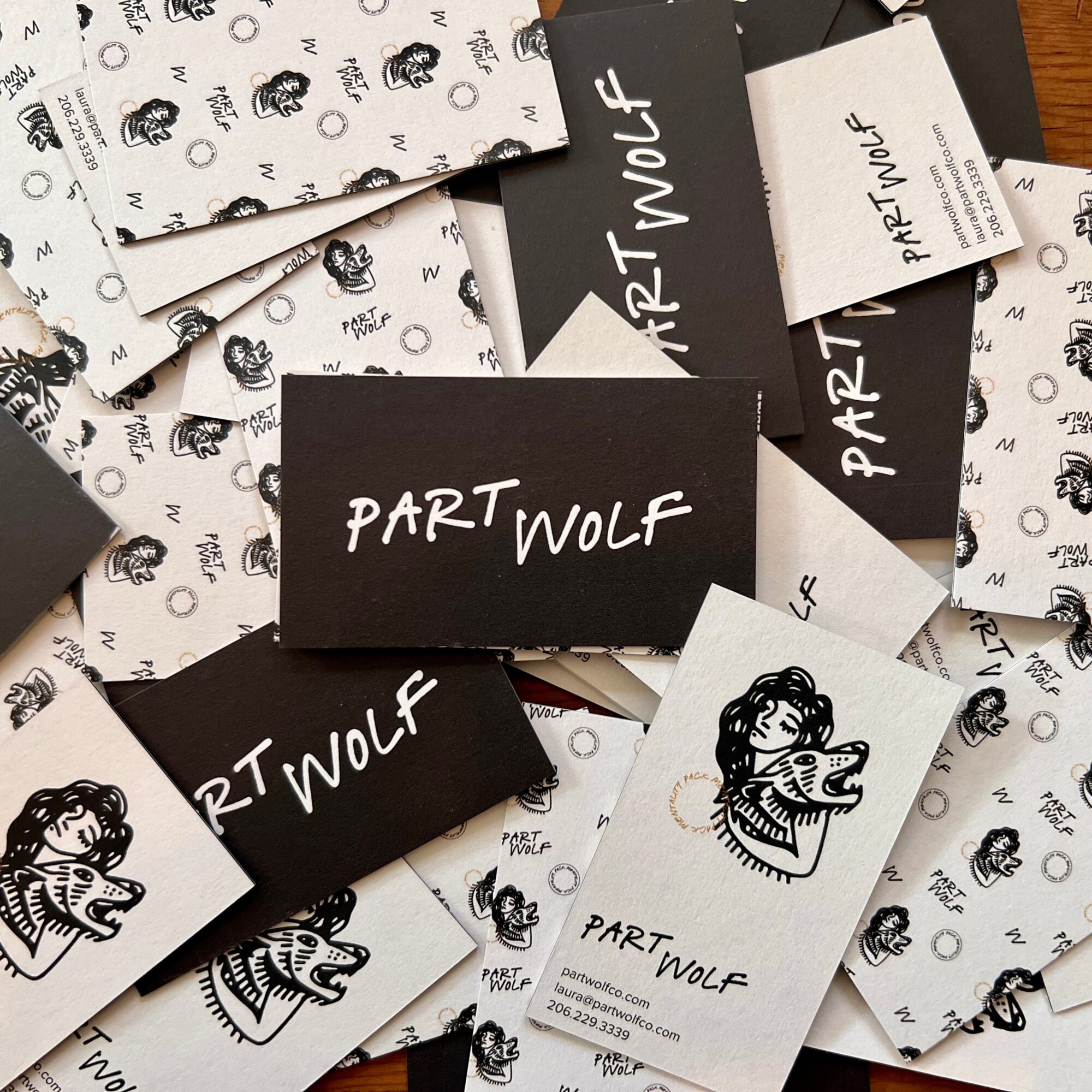 Collection of business cards and paper with 'PART WOLF' text and a wolf illustration, scattered on a surface.