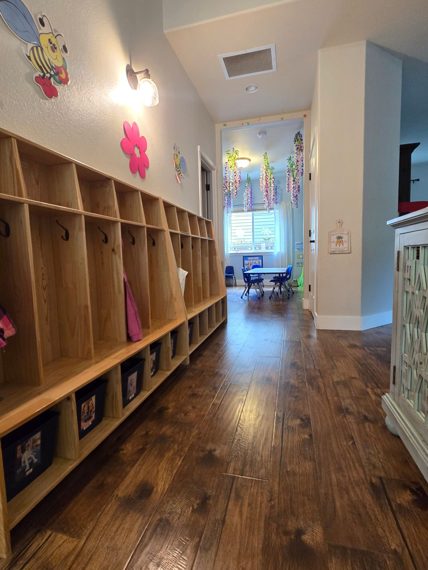 Wooden bookshelf with books and framed photos in a room with hardwood floor and a window with curtains.
