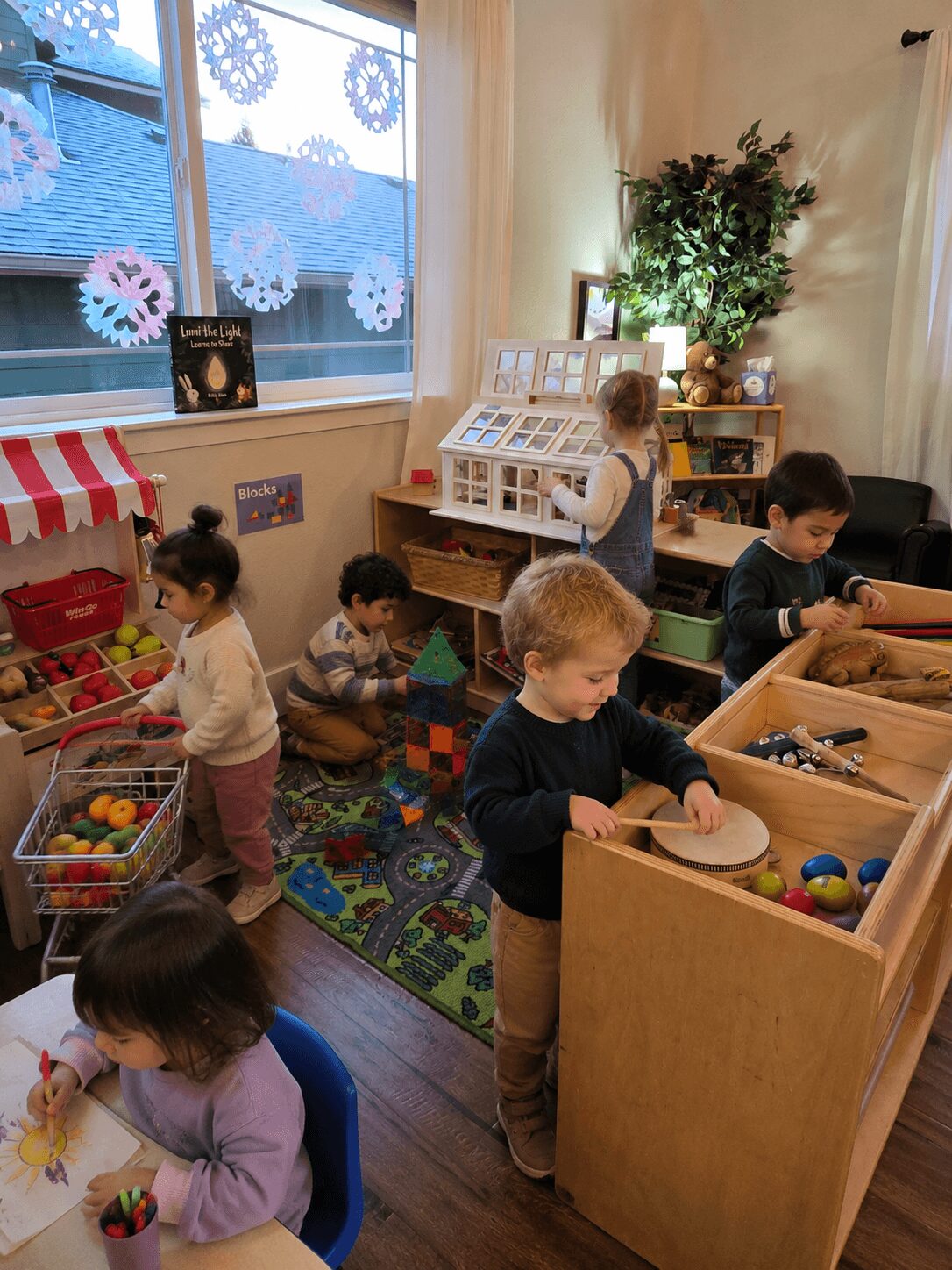 Children playing with toys and blocks in a cozy room with a window, bookshelf, and colorful decorations.