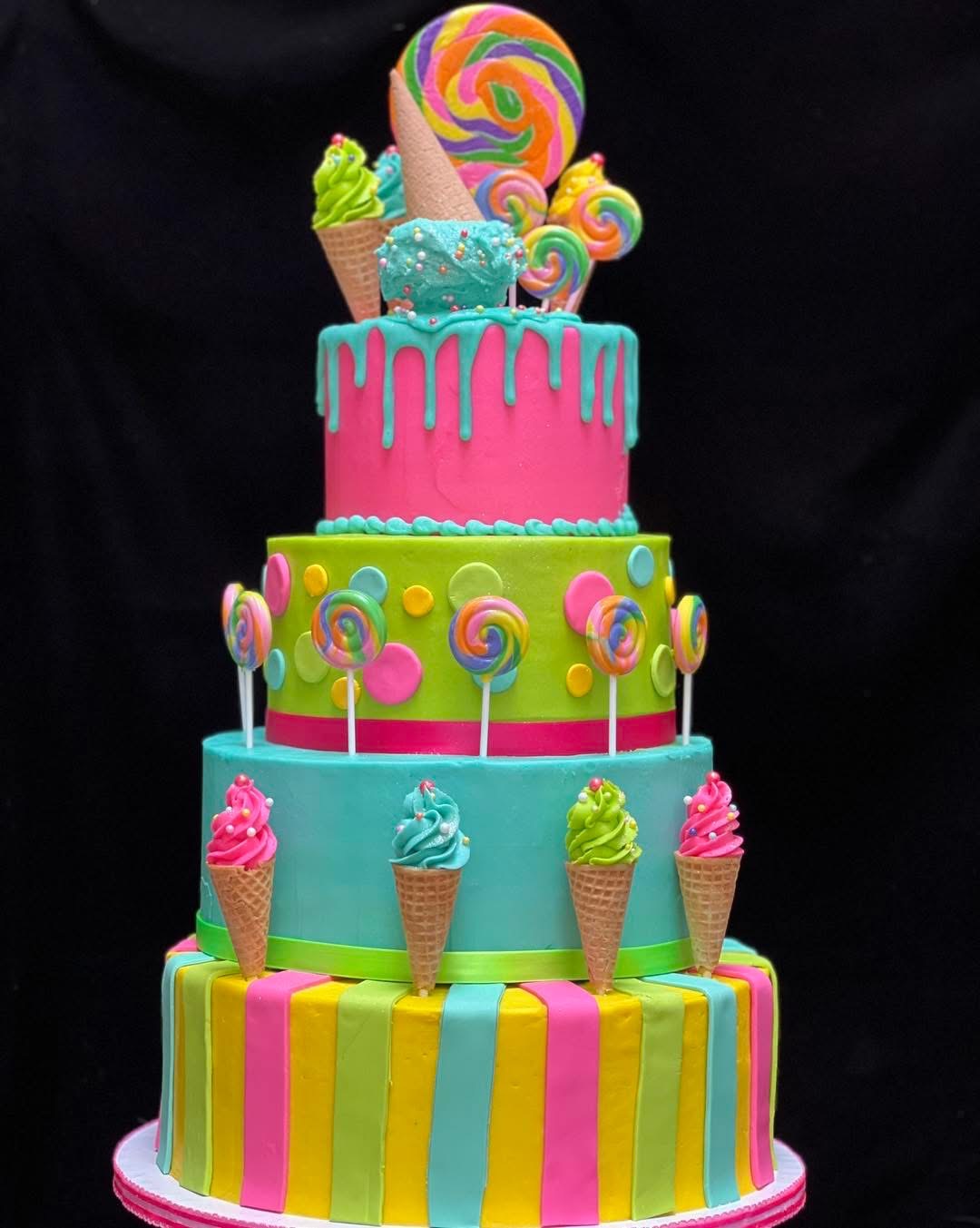 Colorful multi-tiered cake with lollipop, ice cream, and candy decorations, set against a dark background.