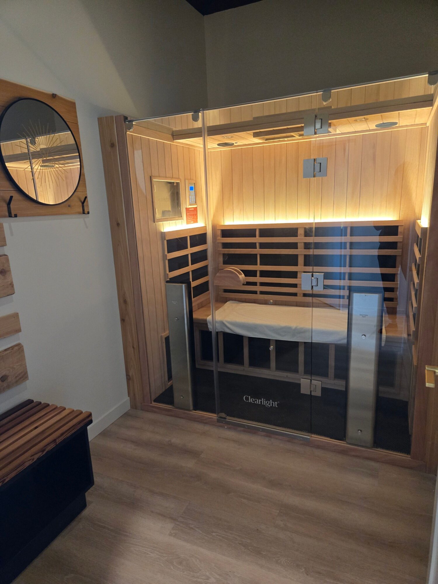 Interior of a sauna room with wooden walls, benches, and a glass door, viewed from outside the room.