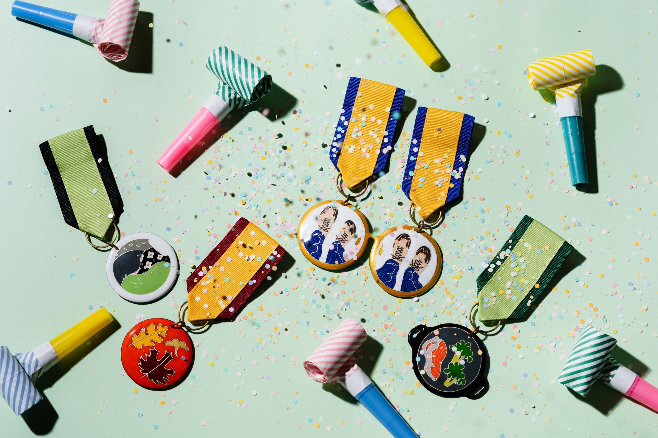 Party hats, medals, and confetti scattered on a light green surface.