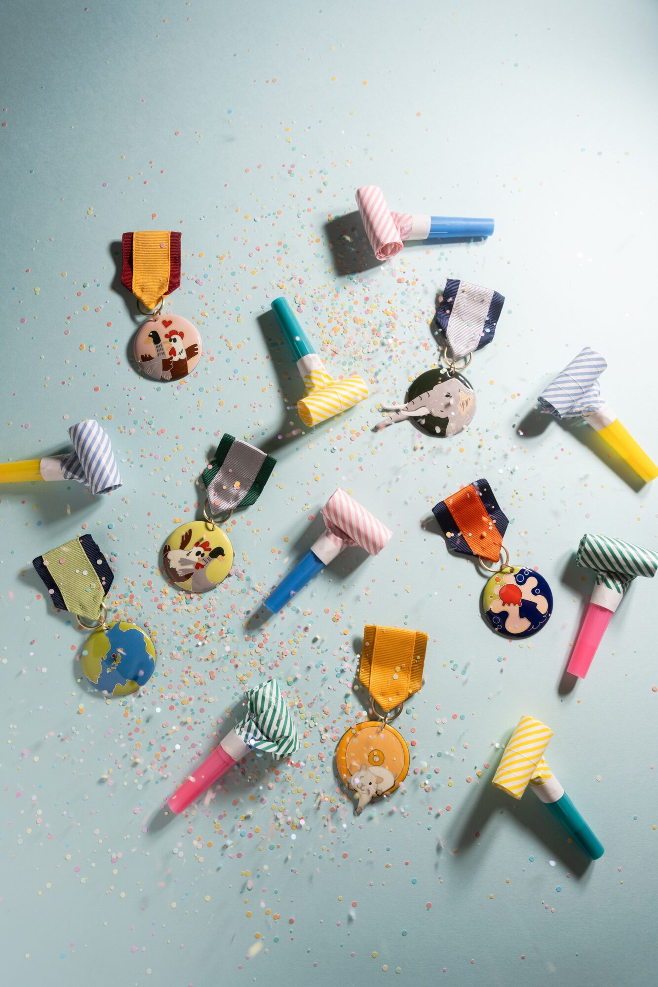 Colorful birthday candles with decorative paper cutouts scattered on a light blue surface, some with glitter and confetti.