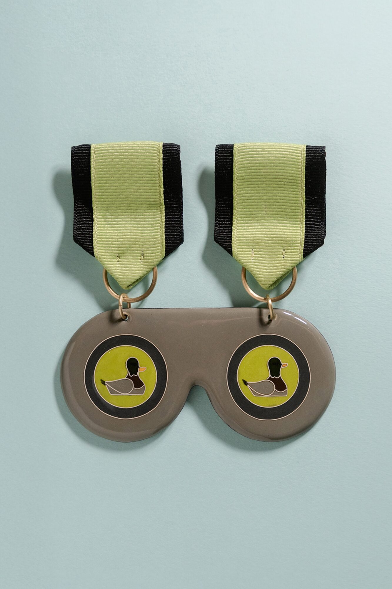 Two medals with yellow and black ribbons, each featuring a person in a boat, on a light blue background.