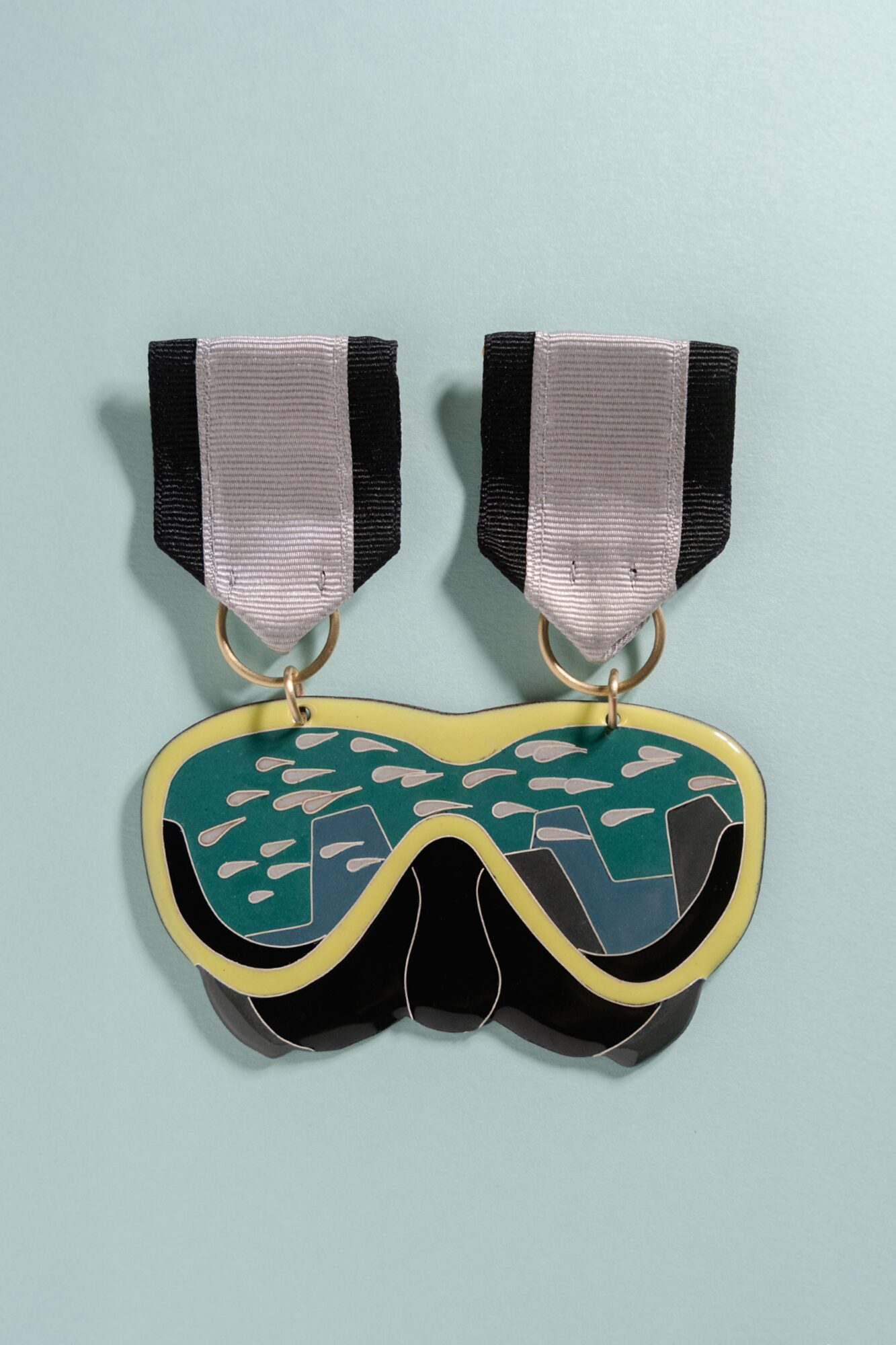 A pair of goggles with black and white straps and a yellow frame, placed on a light blue background.