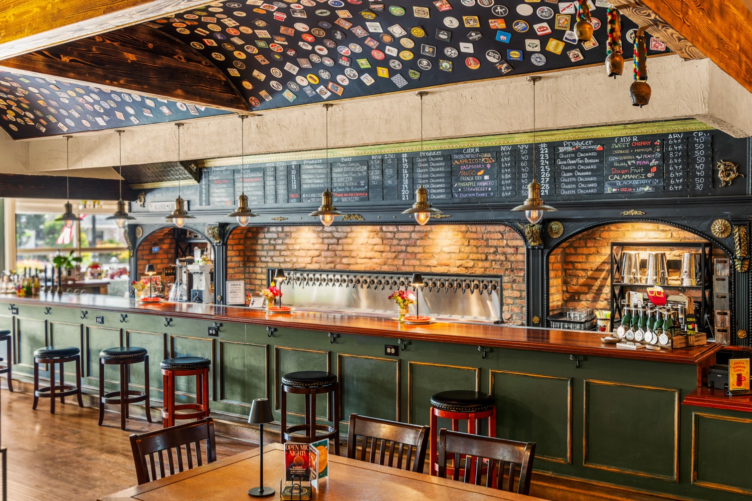Bar with a long counter, chairs, brick arches, menu boards, and decorative ceiling, in a restaurant or cafe setting.
