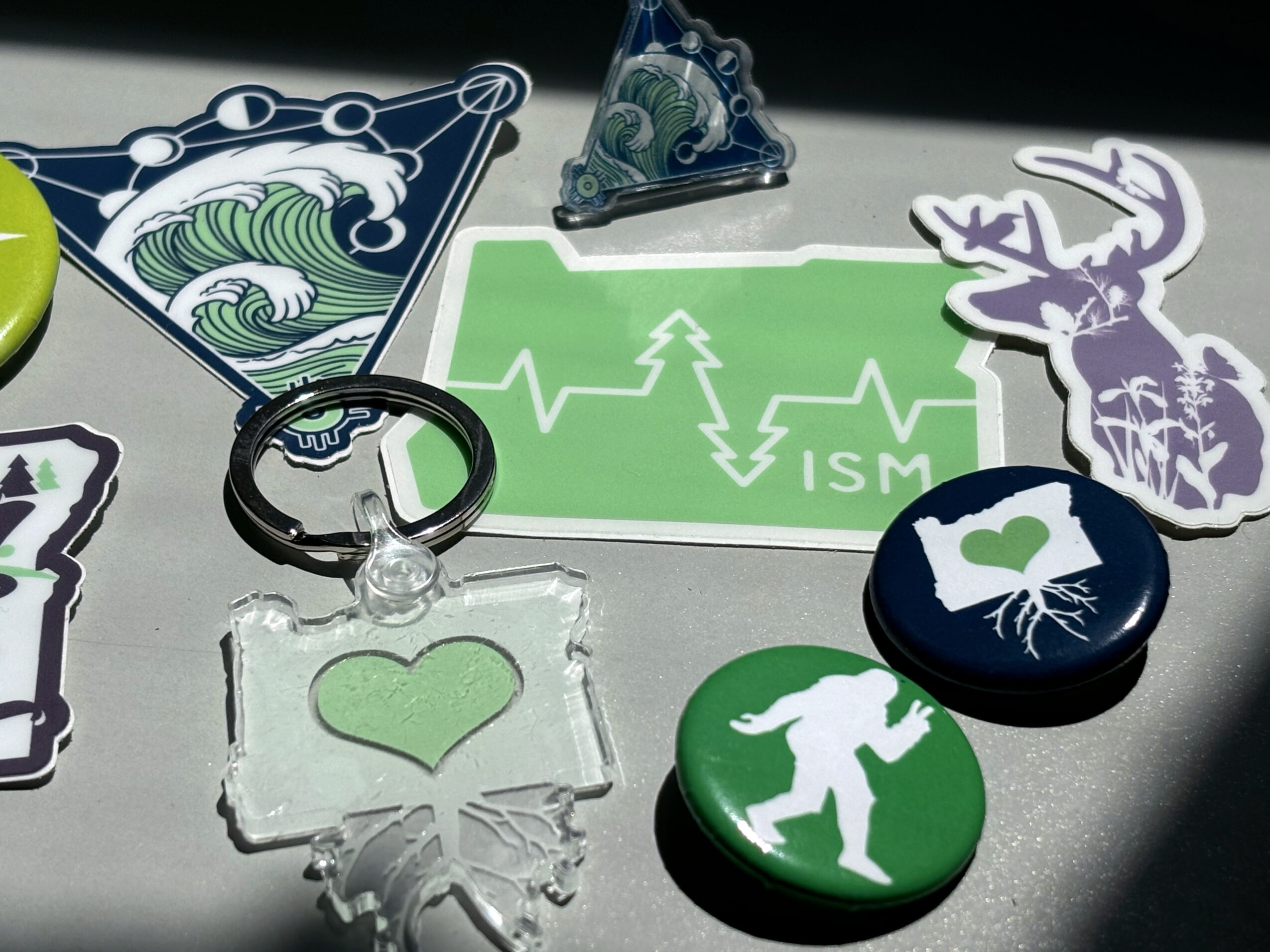 Collection of stickers, tokens, and a keychain with nature and heart themes on a surface.