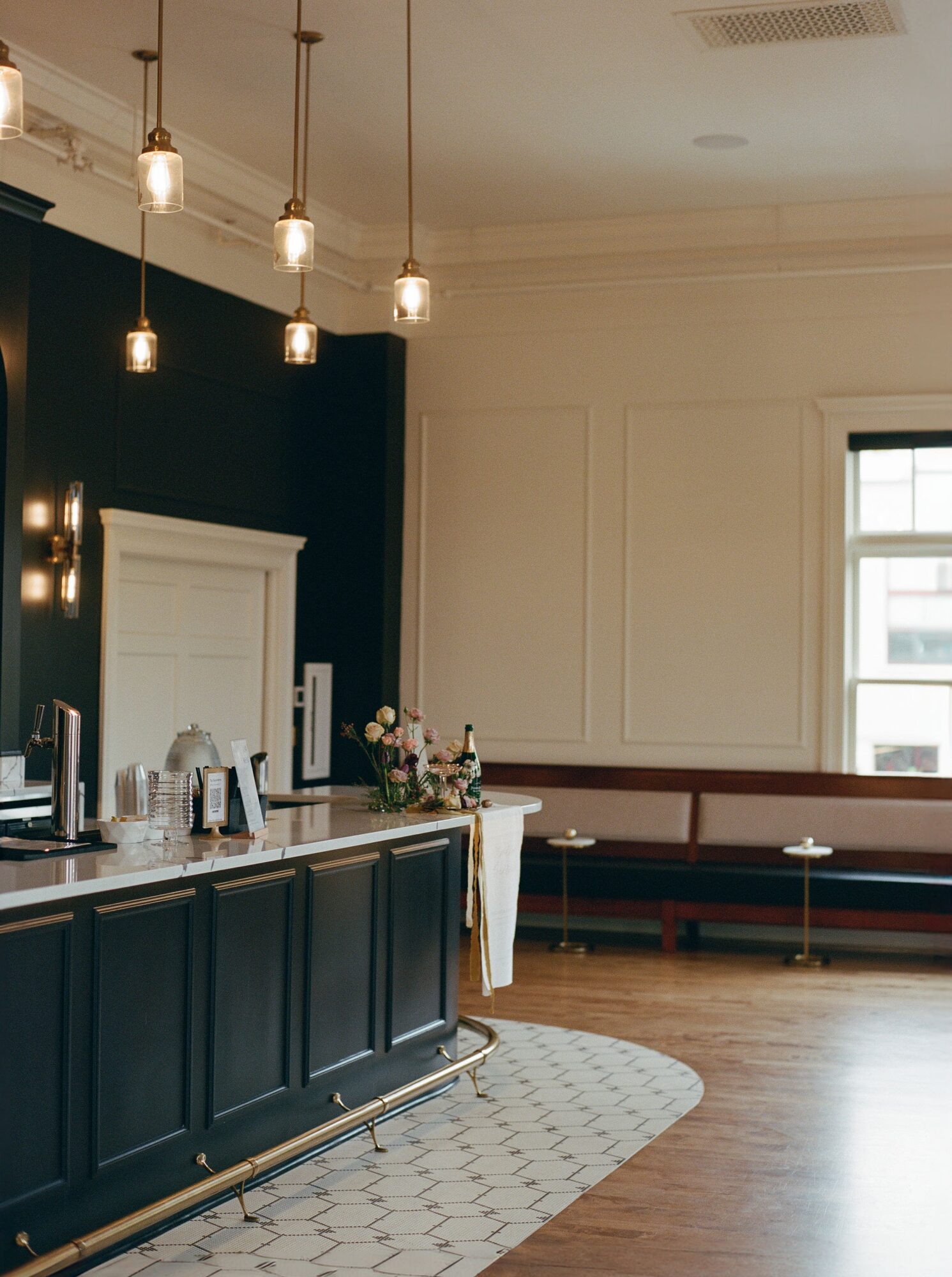Interior of a room with a dark blue counter, hanging lights, a window, and a bench along the wall.