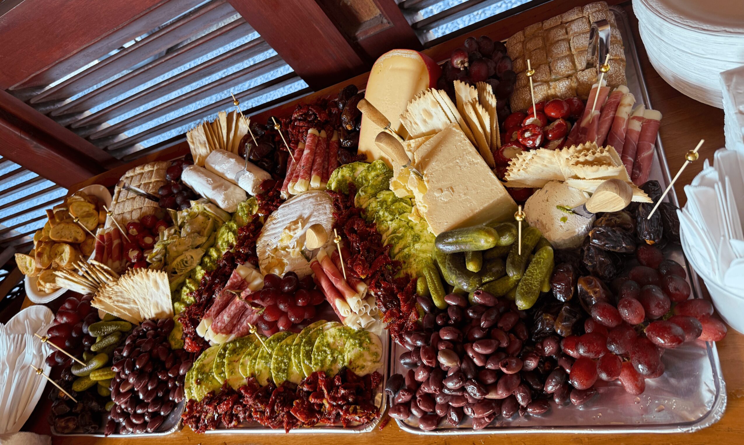 Assorted cheeses, grapes, and crackers on a platter with a wooden background.