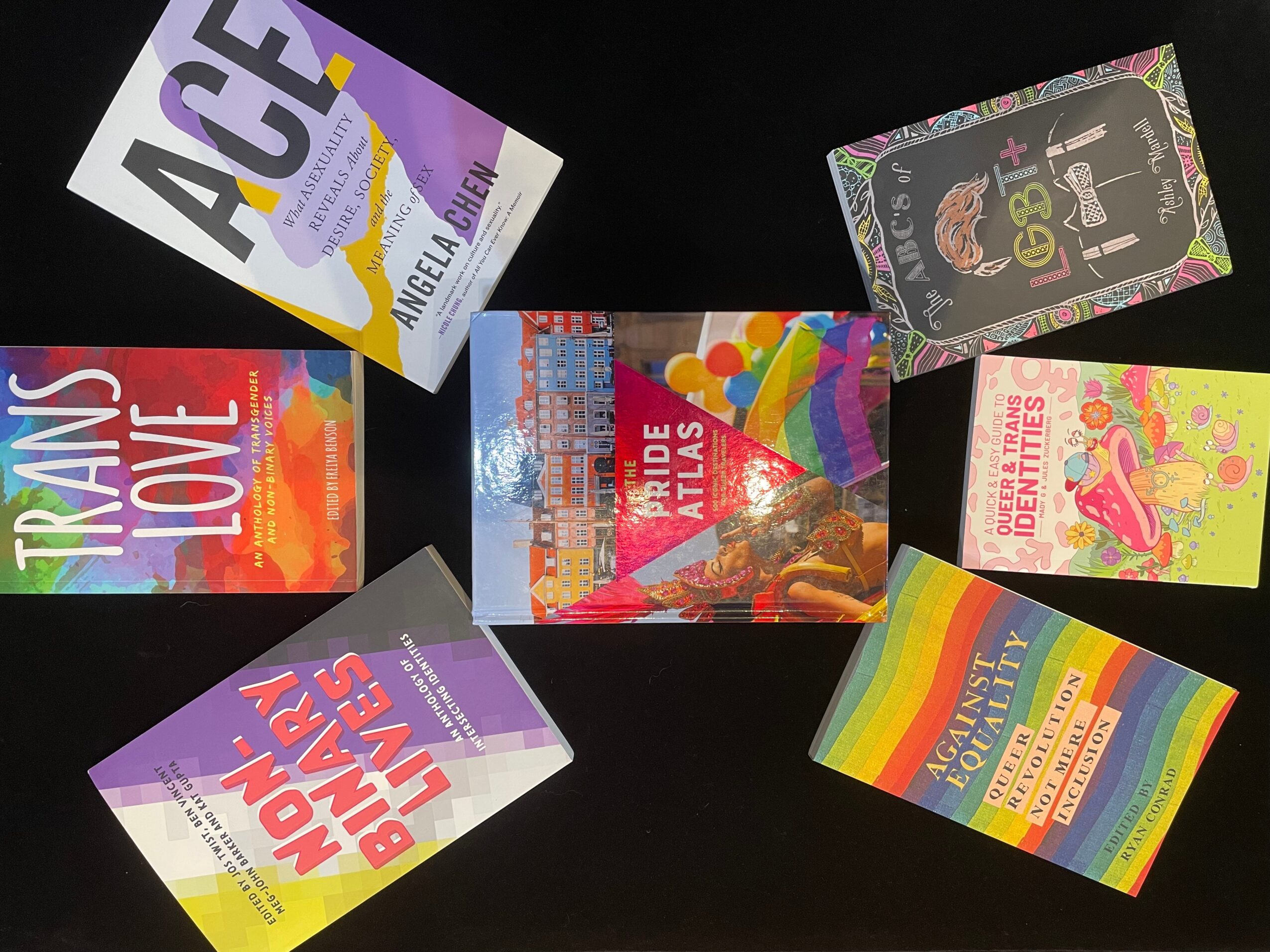 Six colorful books or magazines with vibrant covers arranged on a black background.