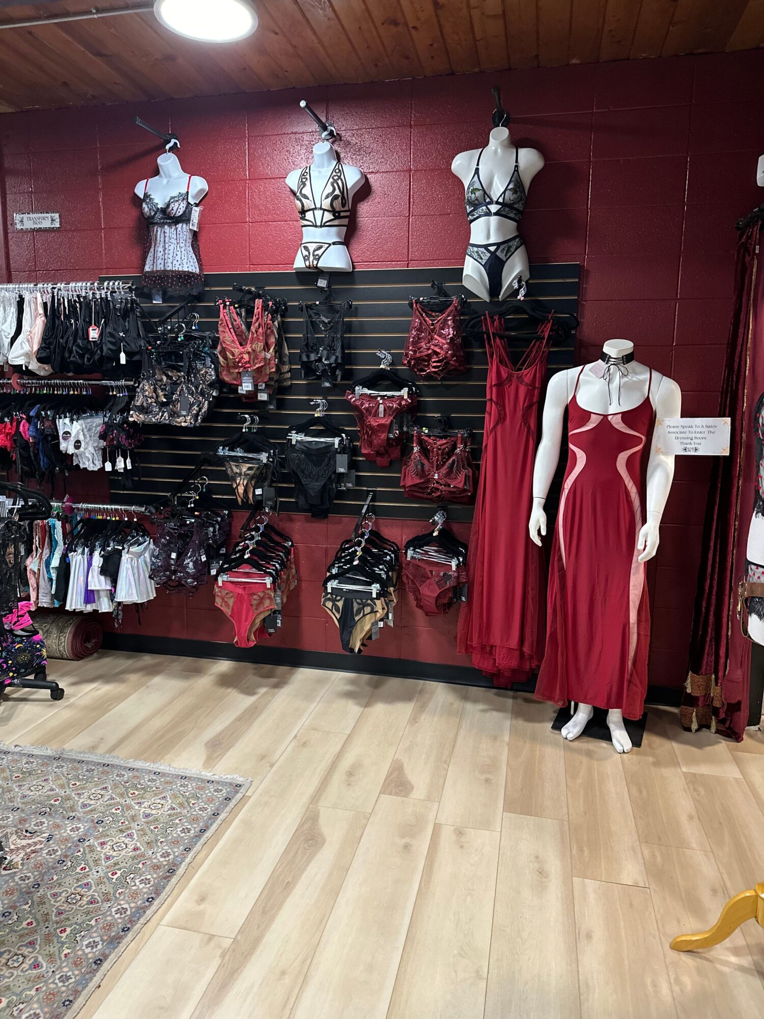 Display of mannequins dressed in red and white clothing, with shelves of accessories and folded clothes, in a retail store.