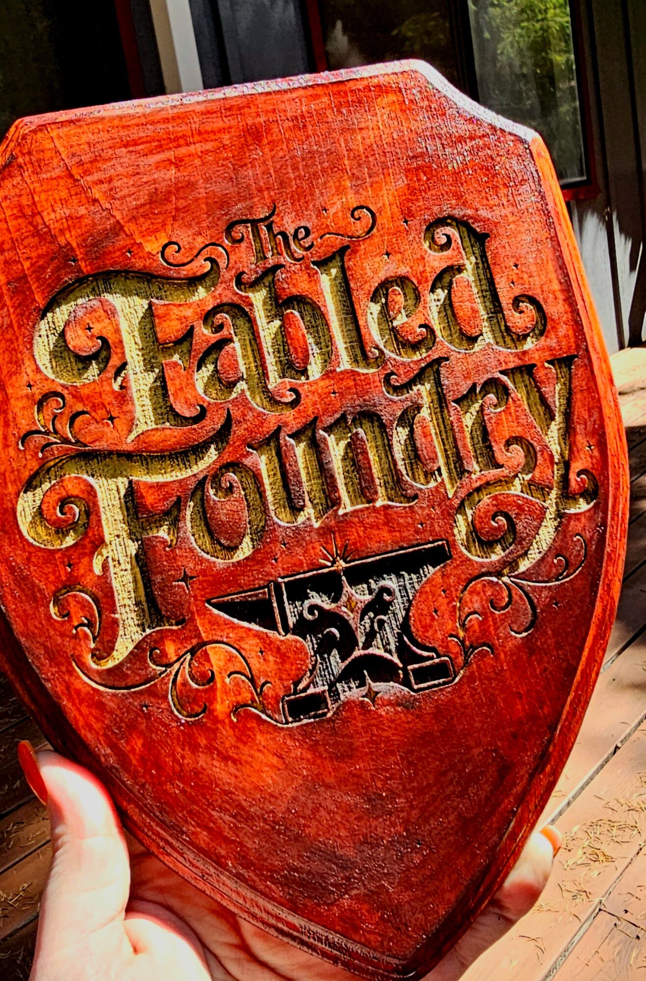 Red shield-shaped sign with black and gold lettering reading 'The Talbot Foundry' and an anvil illustration.