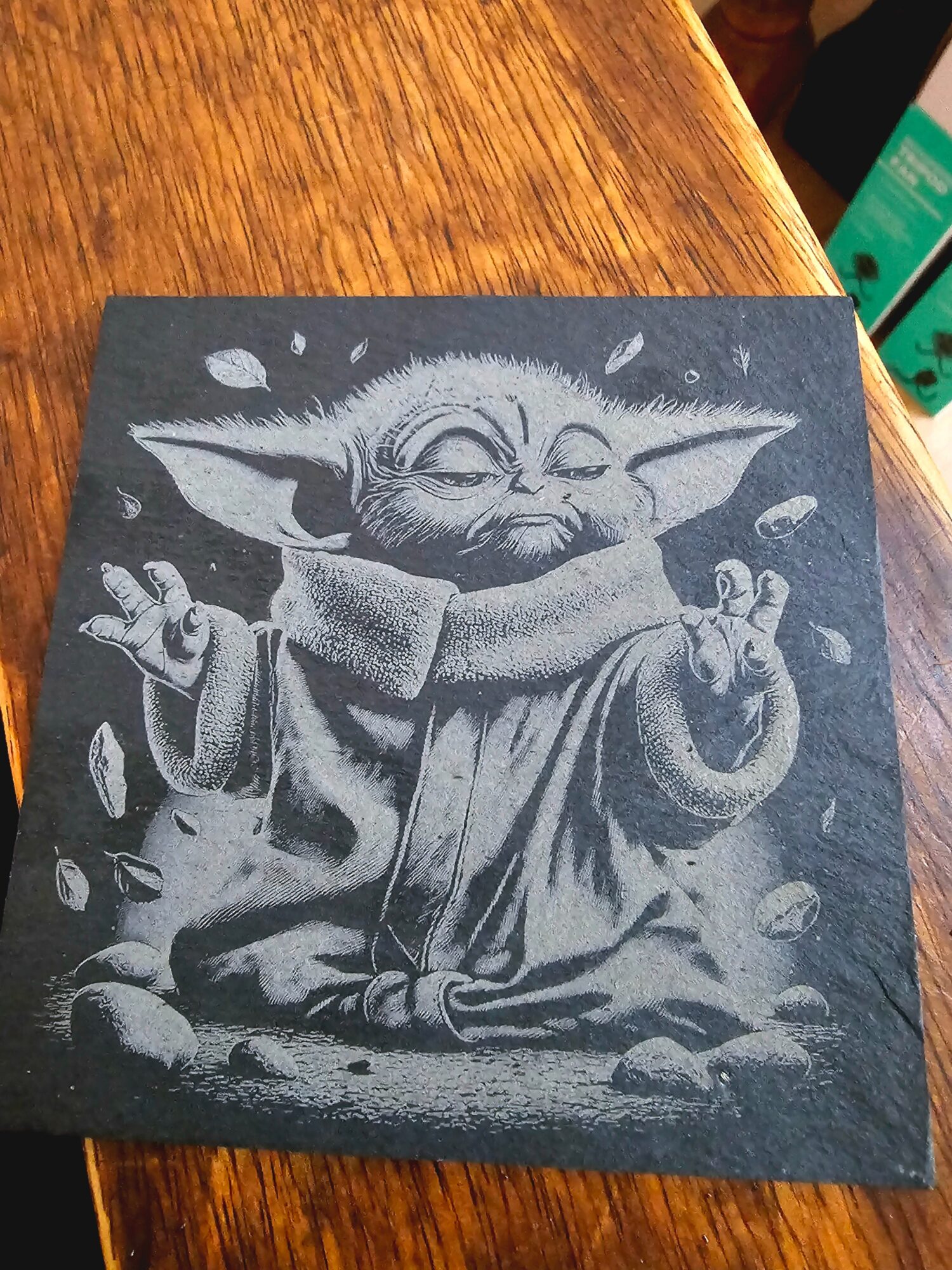 Black and white illustration of Baby Yoda with closed eyes, arms raised, surrounded by falling leaves or petals.