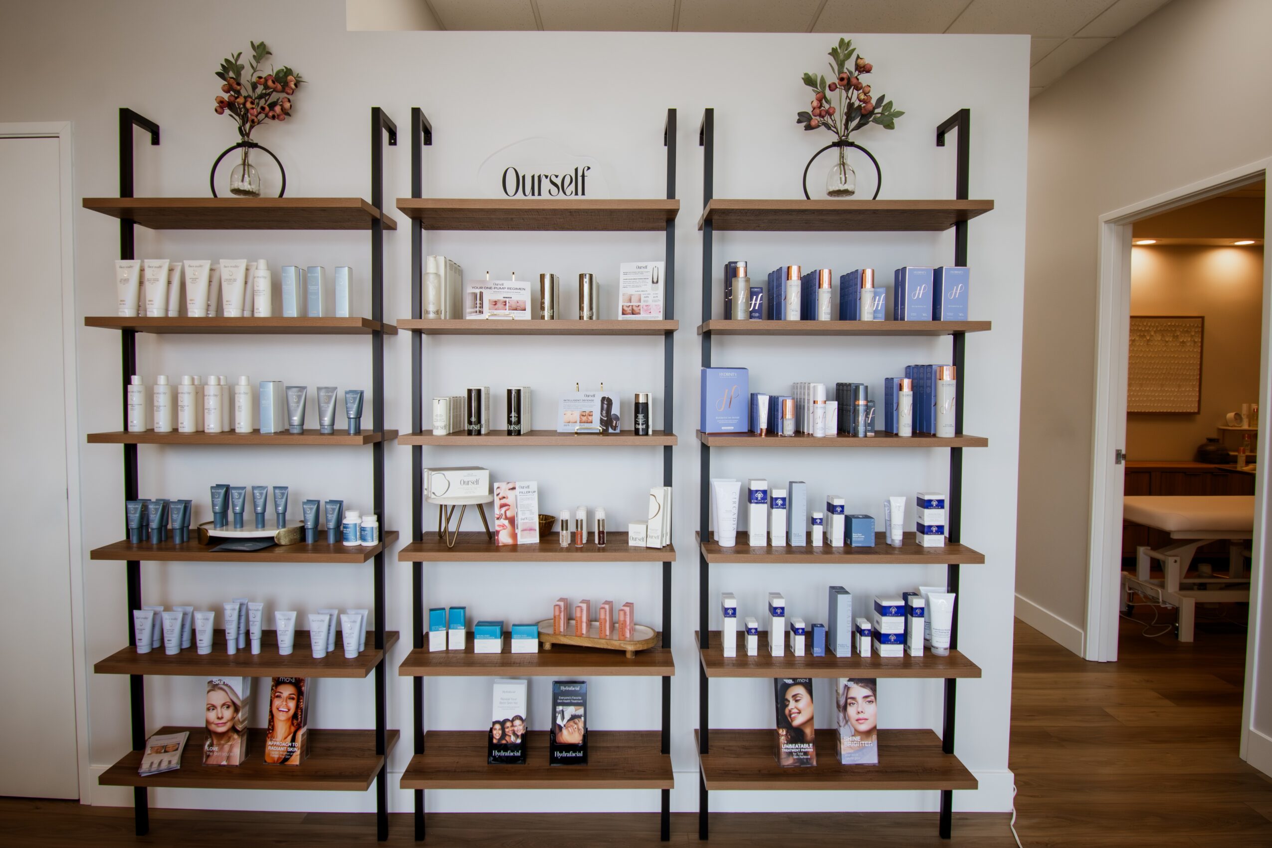 Shelves with skincare products, books, and decorative items against a white wall, with a doorway to the right.