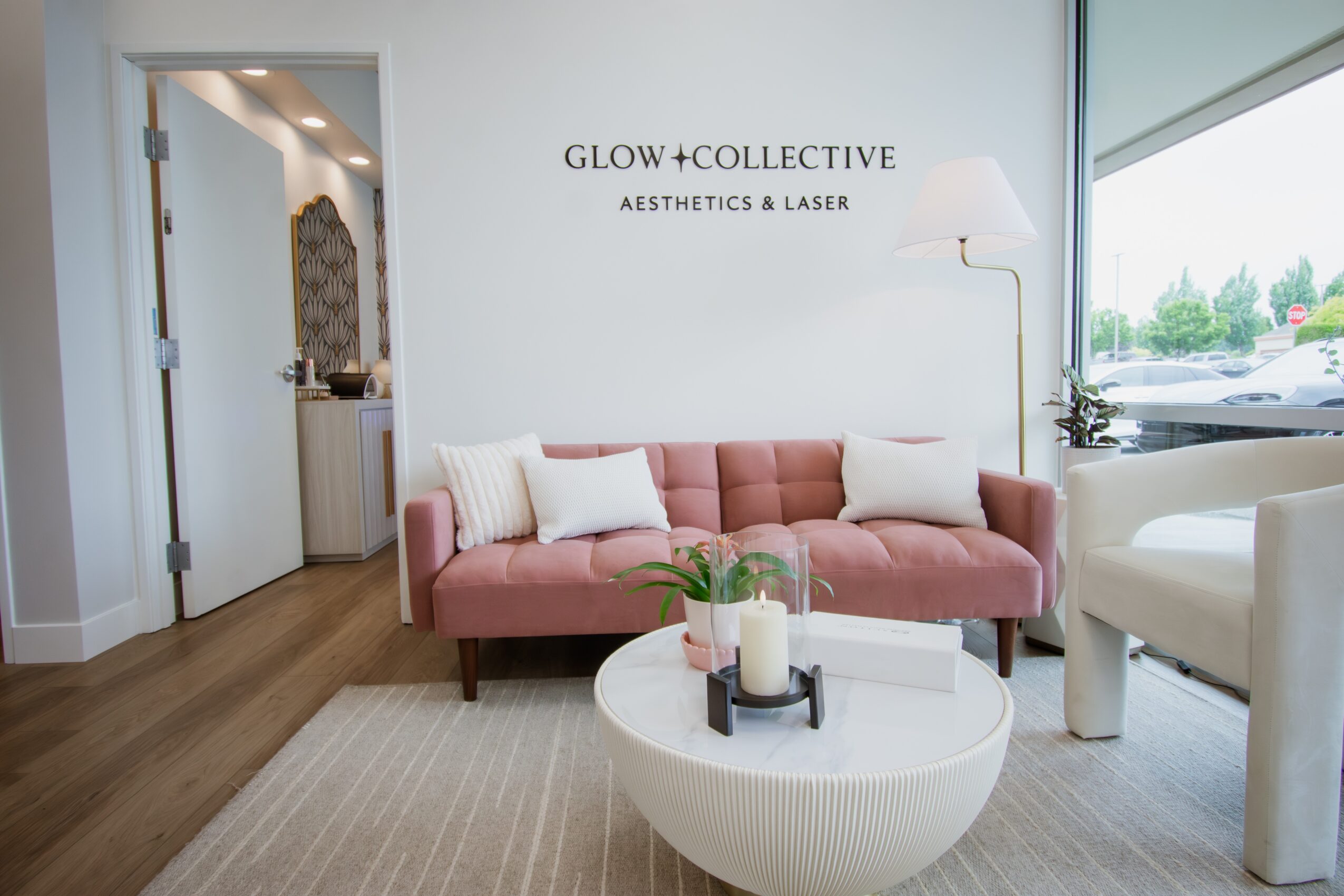 Pink sofa with white pillows in a modern aesthetic room, with a white round coffee table and large window, natural light.