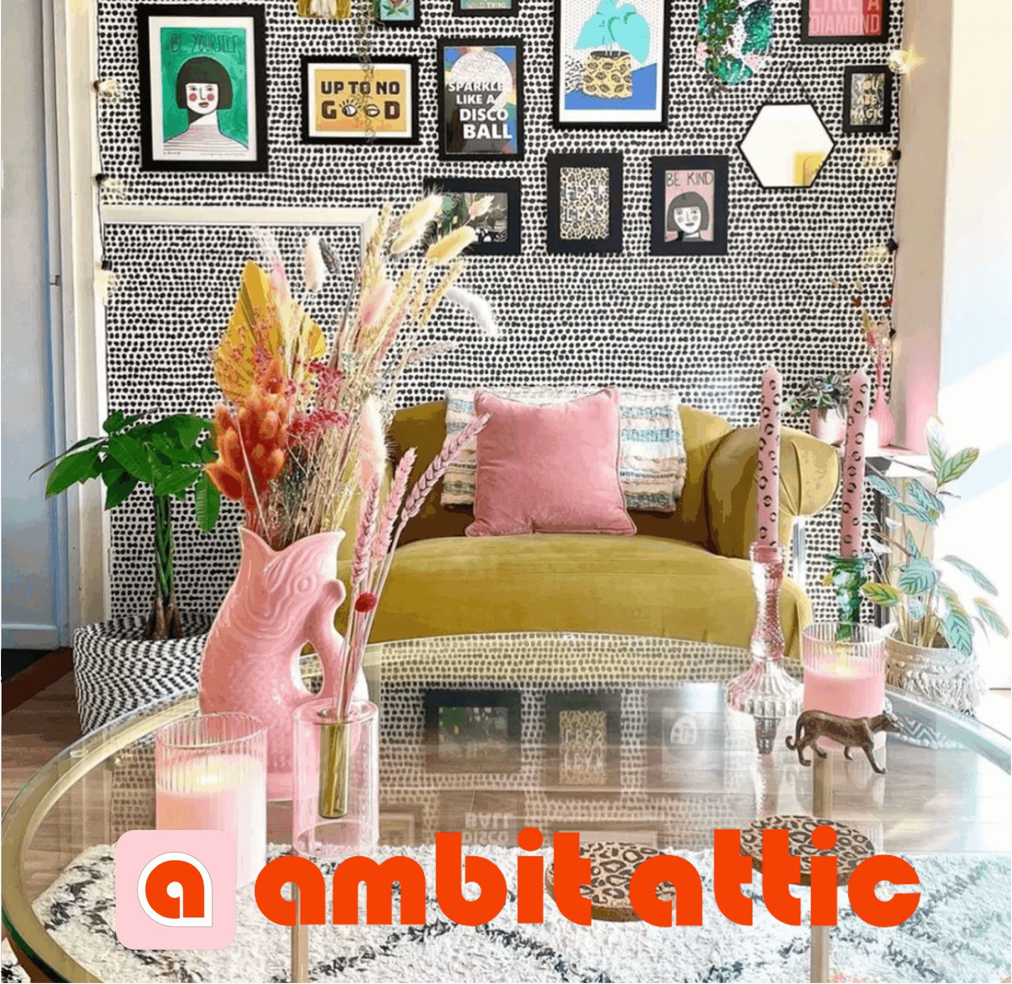 Living room with a green sofa, pink pillows, colorful vases with flowers, and a gallery wall with framed pictures.