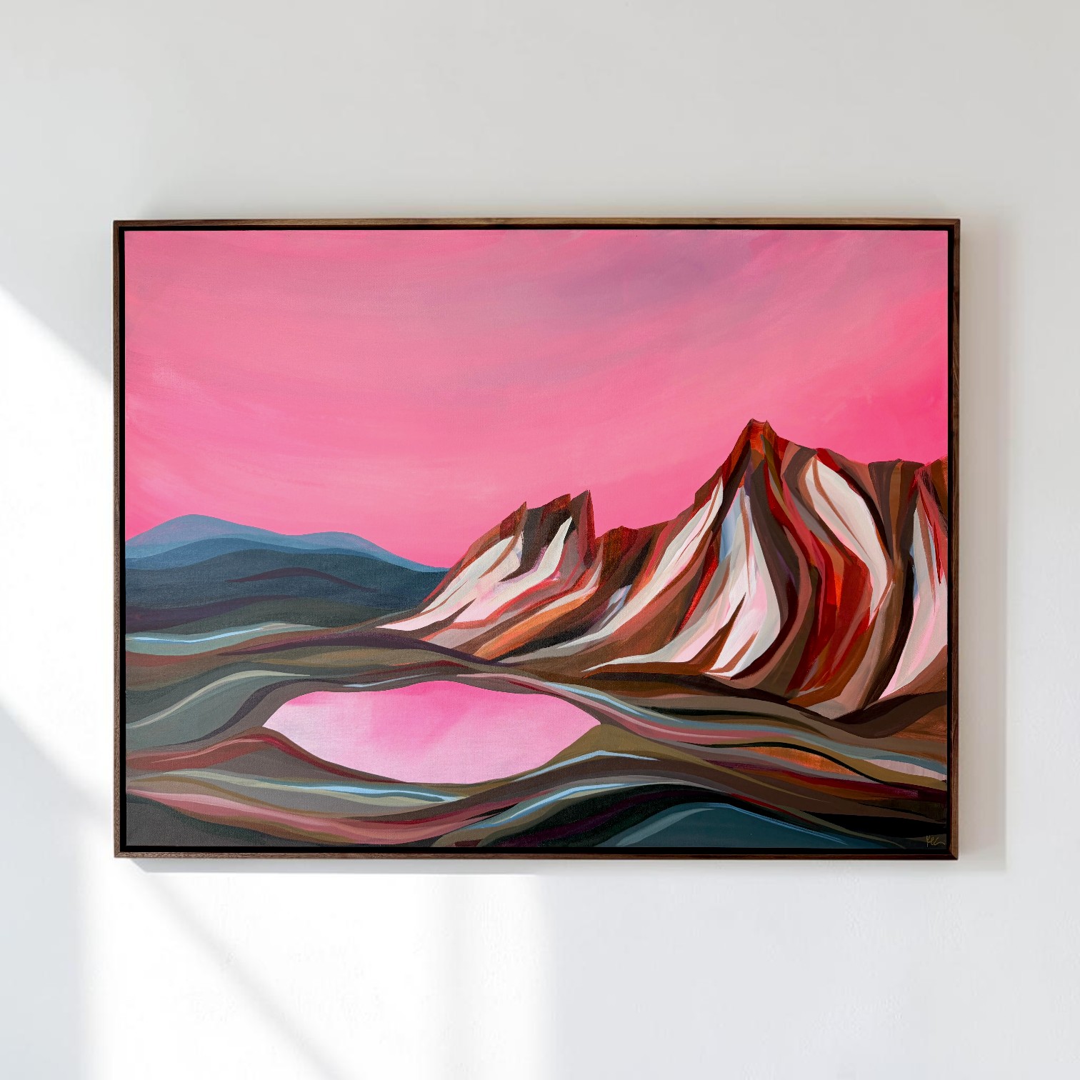 Abstract landscape painting with mountains, lake, and pink sky, framed and hung on a white wall.