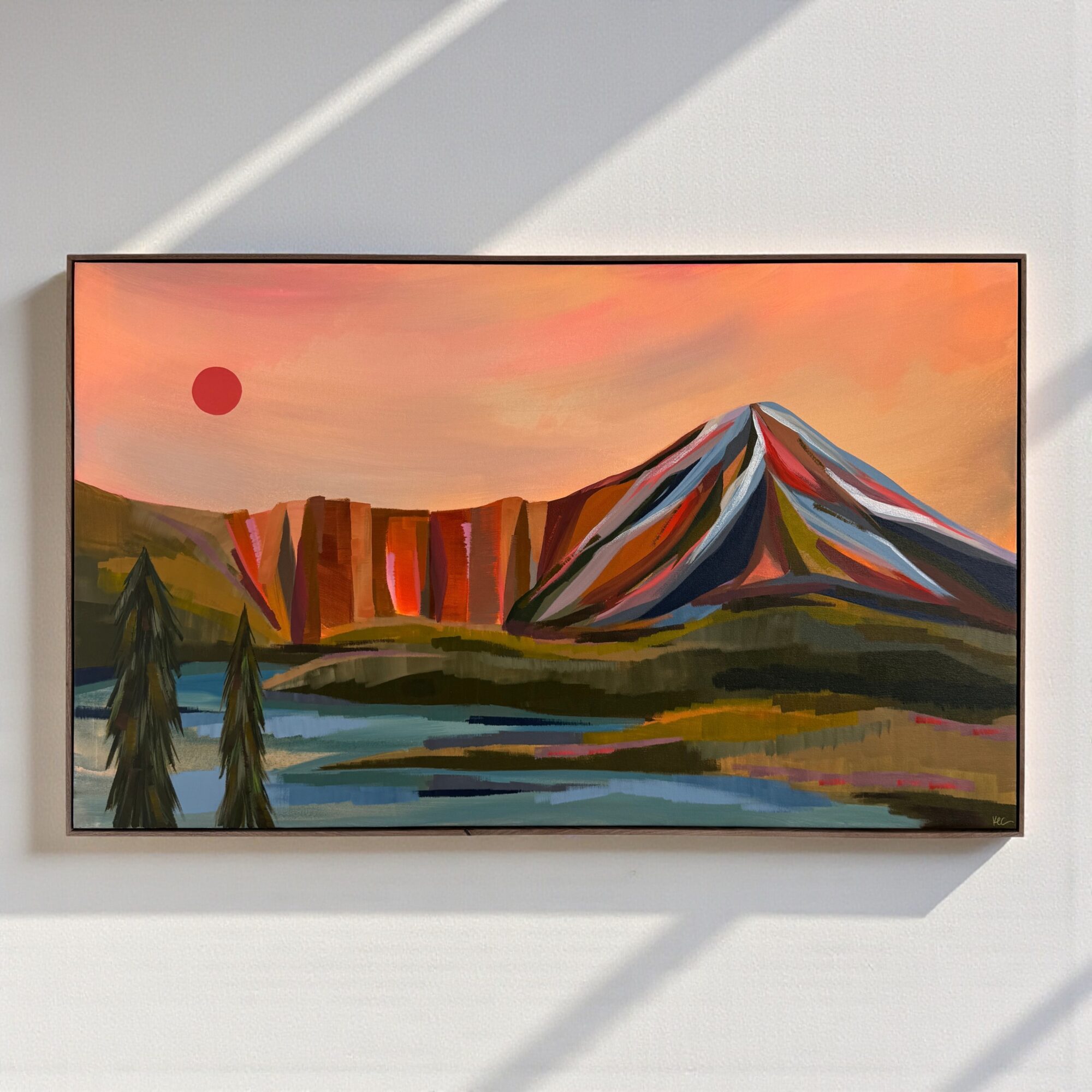 Landscape painting of a mountain, cliffs, trees, and a body of water with a red sun in a pink-orange sky.