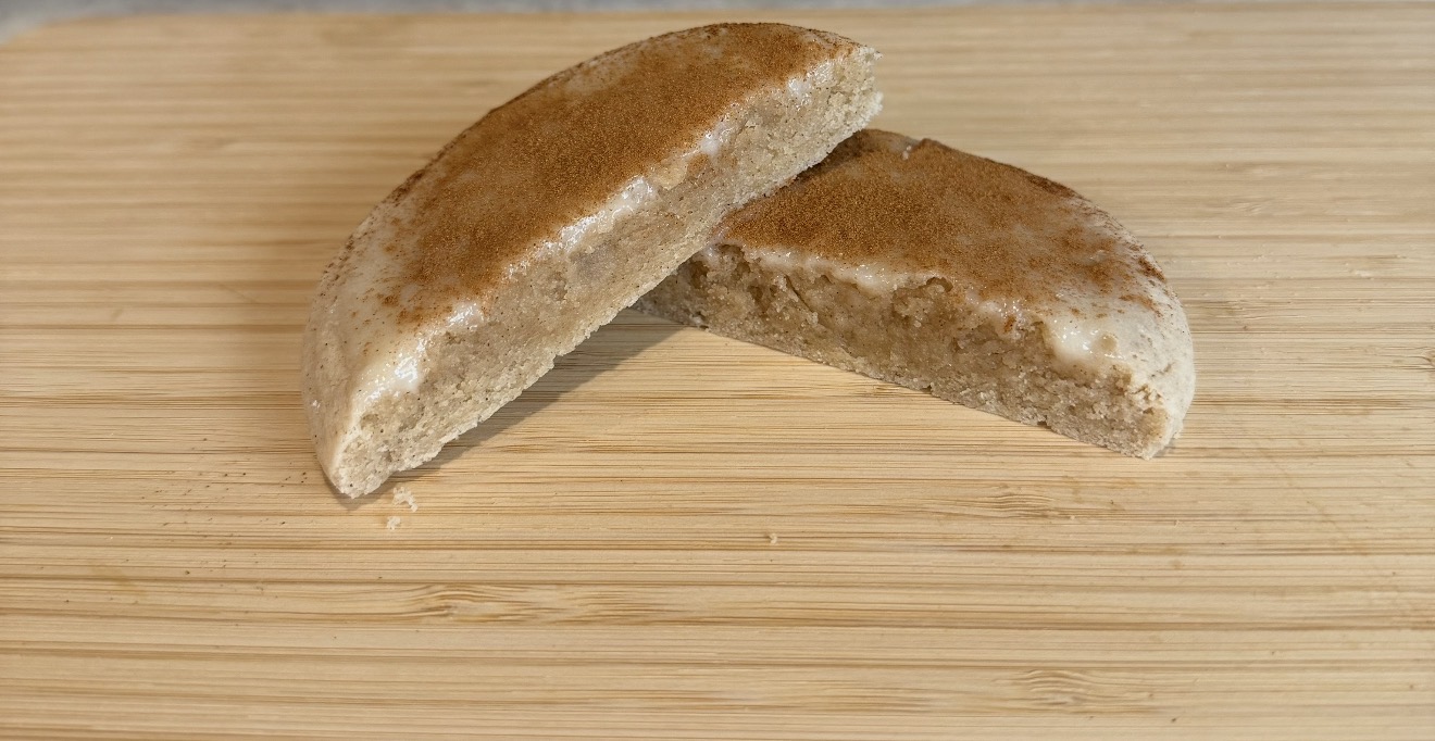 Two bread rolls on a wooden surface, one partially broken, with a golden-brown crust.
