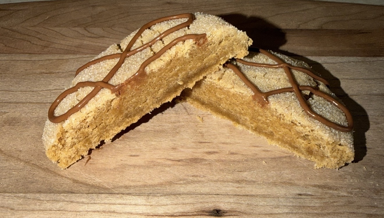 Two slices of cake with chocolate drizzle on a wooden surface.
