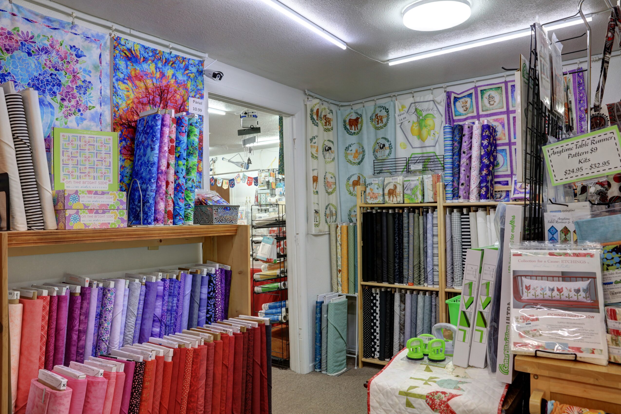 Store interior with colorful fabric rolls, craft supplies, and wall decorations, viewed from the front, well-lit and organized.