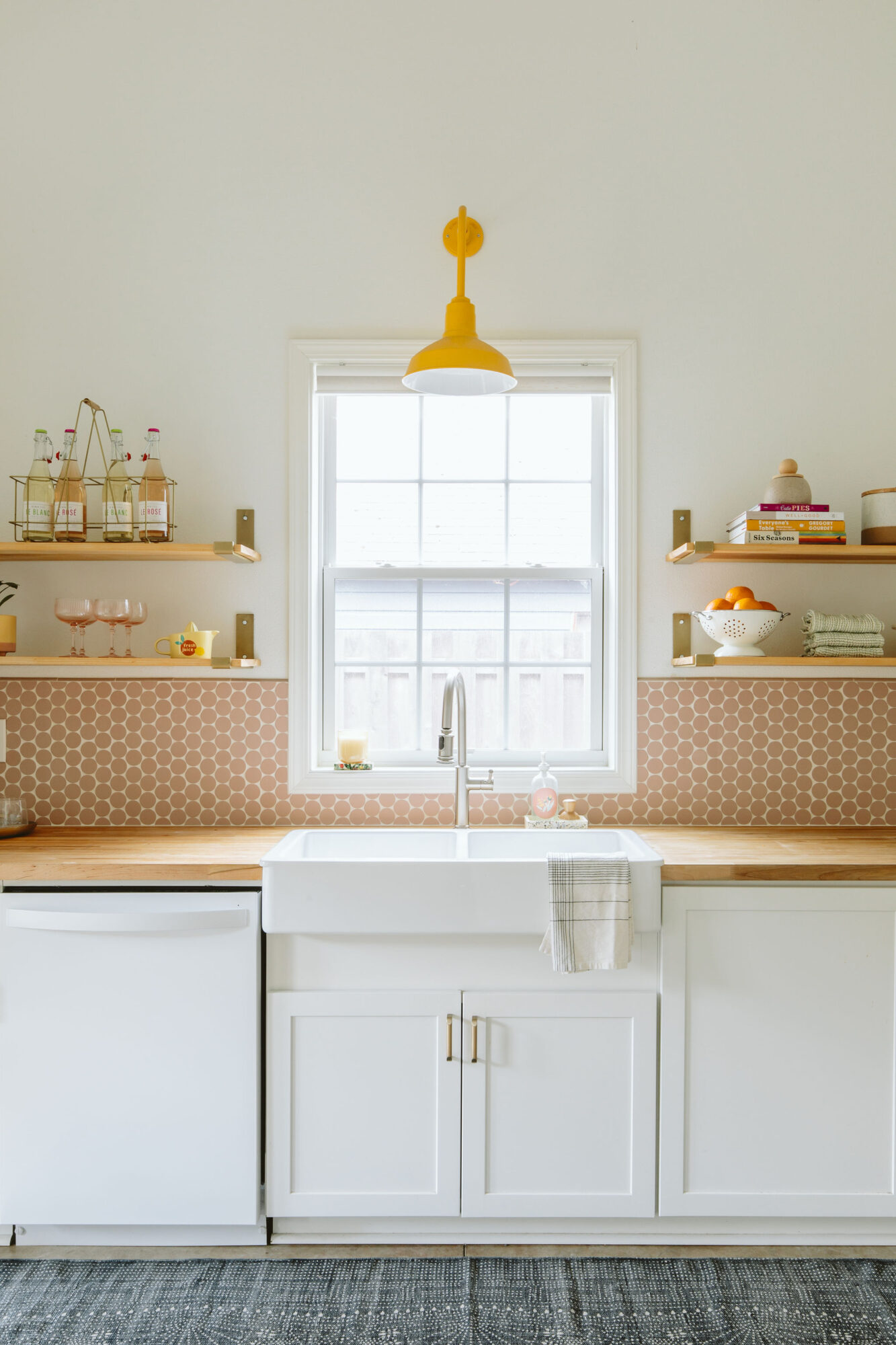 Kitchen with white cabinets, open shelves, a window, and a yellow pendant light, with a white farmhouse sink and countertop.