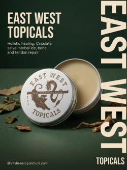 Open tin of East West Topicals balm with label, surrounded by dried herbs and leaves, on dark green background.