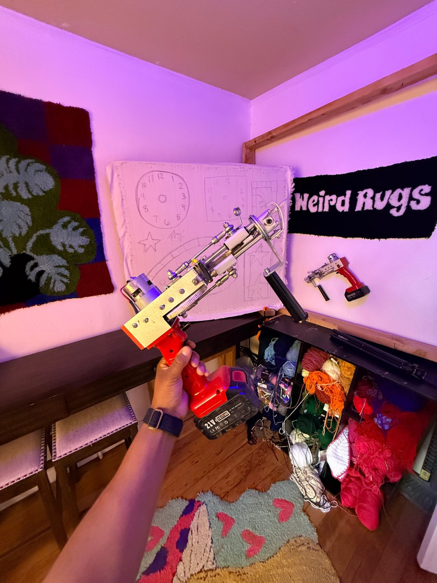 Person holding a syringe with a yellow and red device, with a table and shelves in the background.