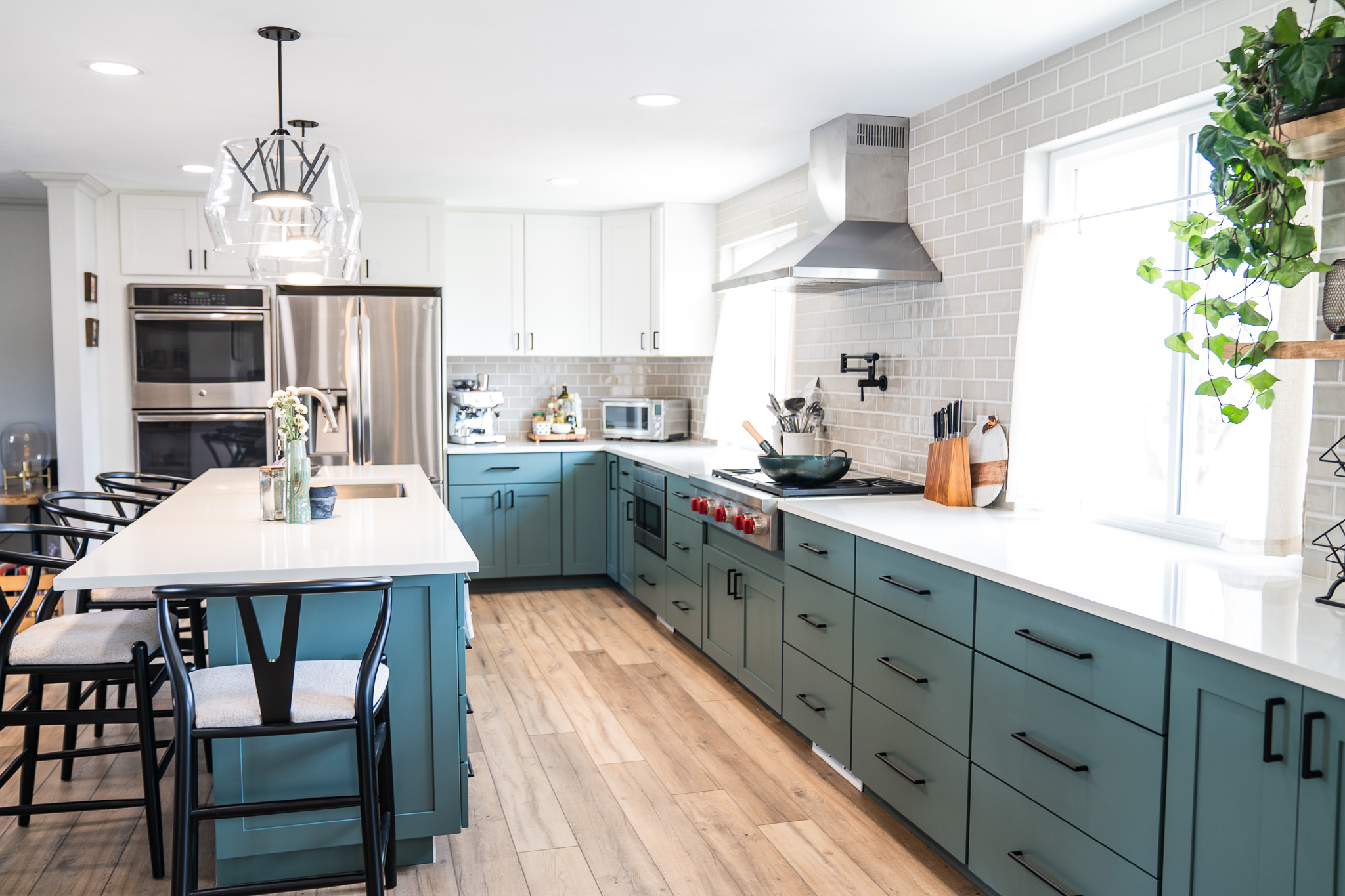 Modern kitchen with white upper cabinets, blue lower cabinets, stainless steel appliances, and wooden flooring.