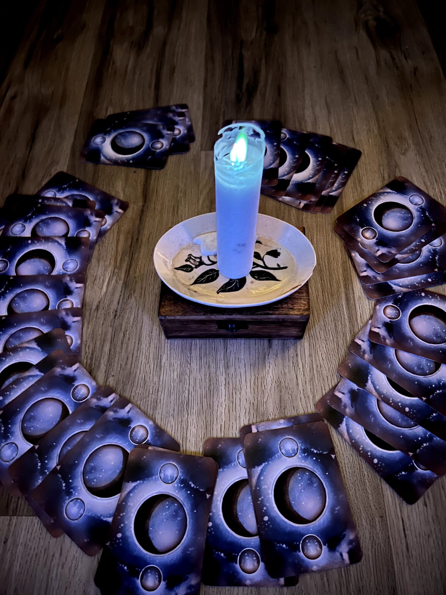 Cards arranged in a circle around a lit candle on a wooden surface.