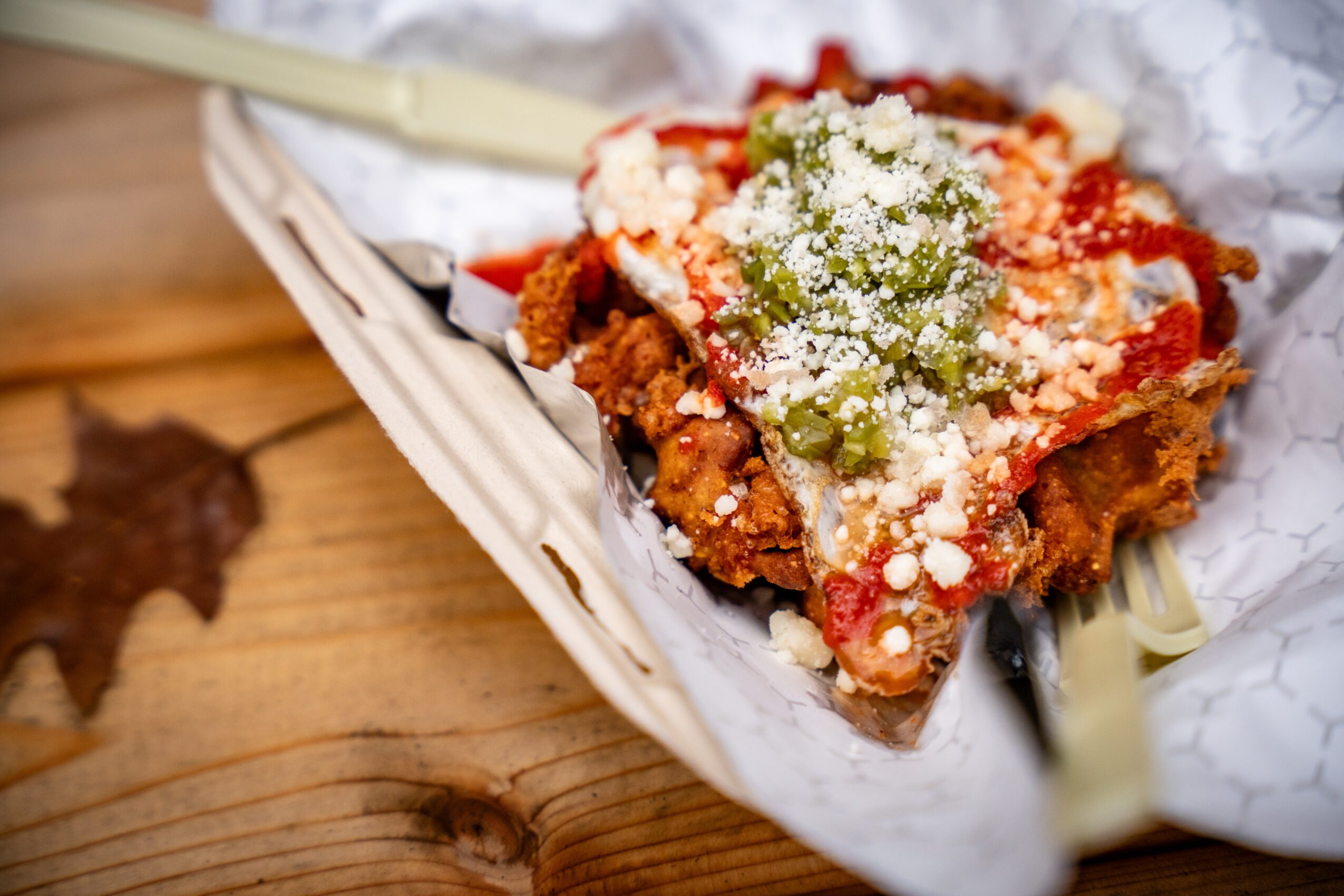 Slice of pizza with cheese, green peppers, and tomato sauce in a basket on a wooden surface.