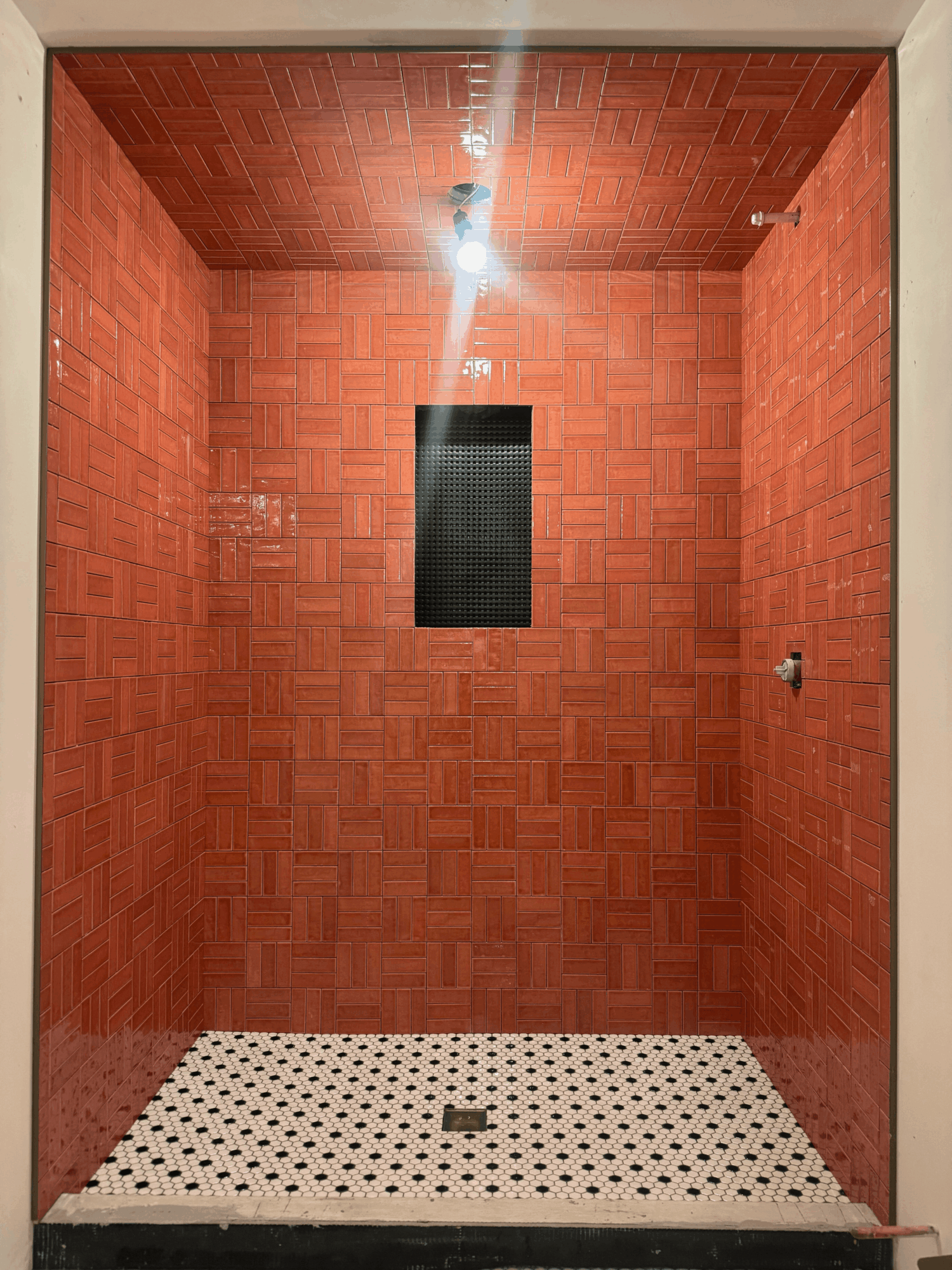 Small room with red brick walls, black window, white tiled floor, and ceiling light fixture.