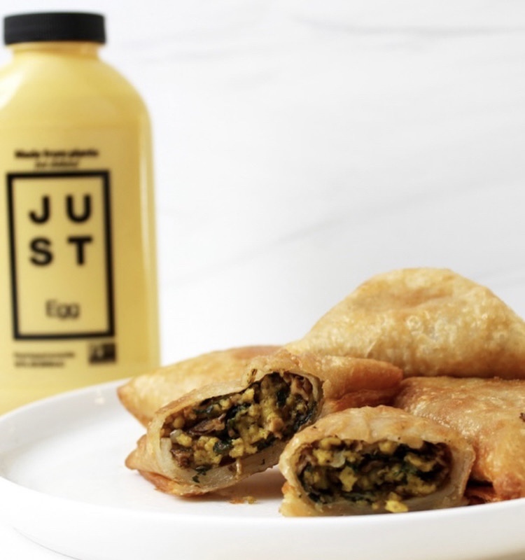 Plate with fried food, filling visible, and a yellow bottle in the background, on a white surface.