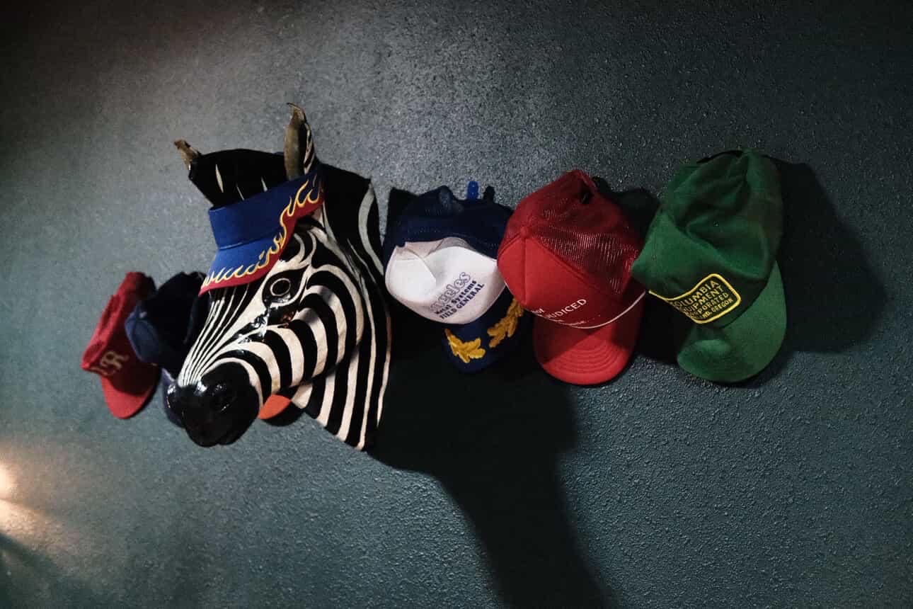 Six hats and a sock with a zebra pattern are lined up on a dark surface.