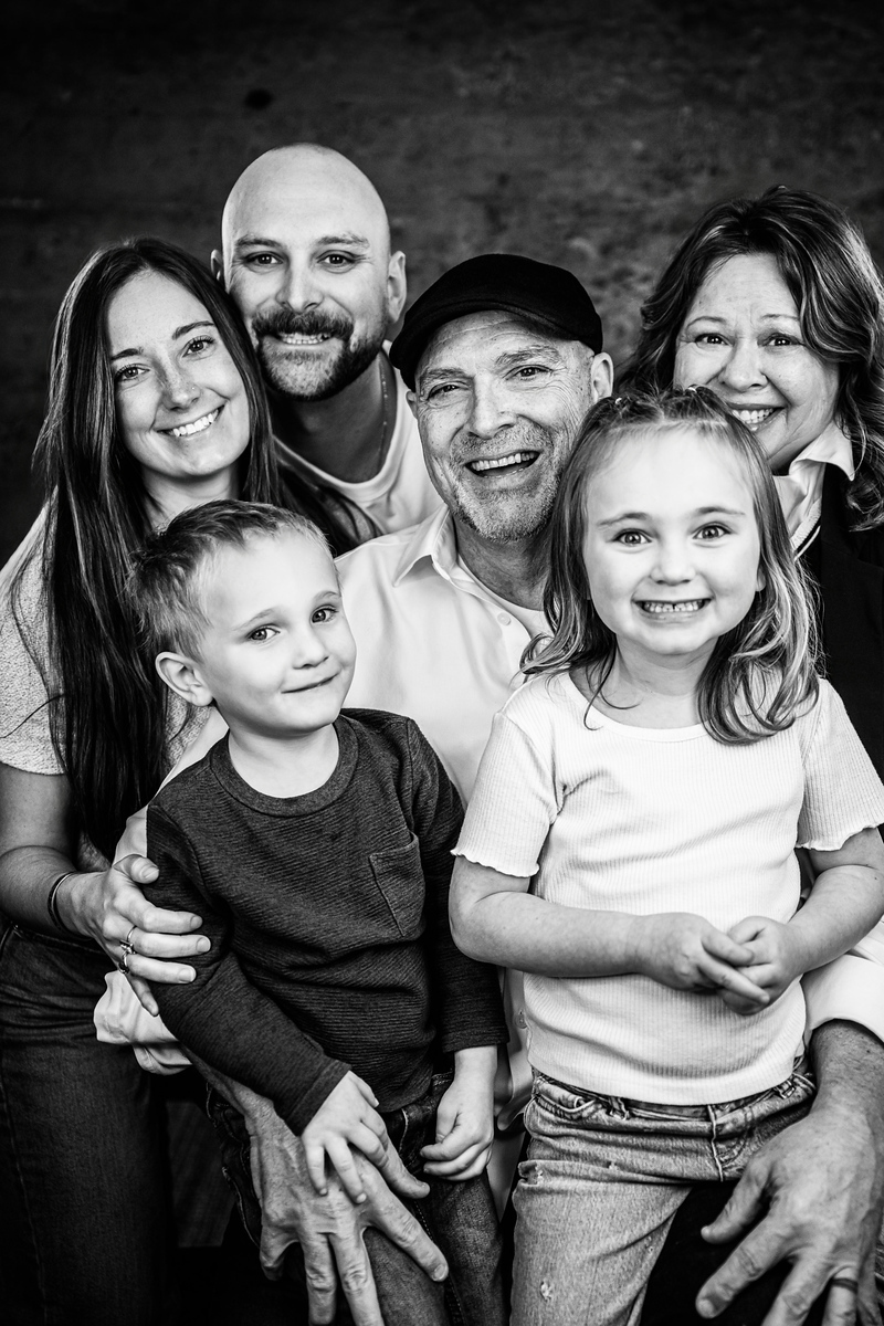 Group of six people, including children and adults, smiling together in a black-and-white photo.