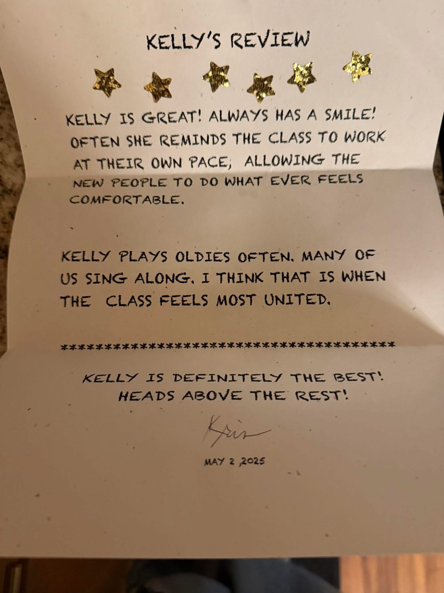 Review of Kelly with gold star stickers, praising her teaching and class unity, signed and dated May 2, 2023.