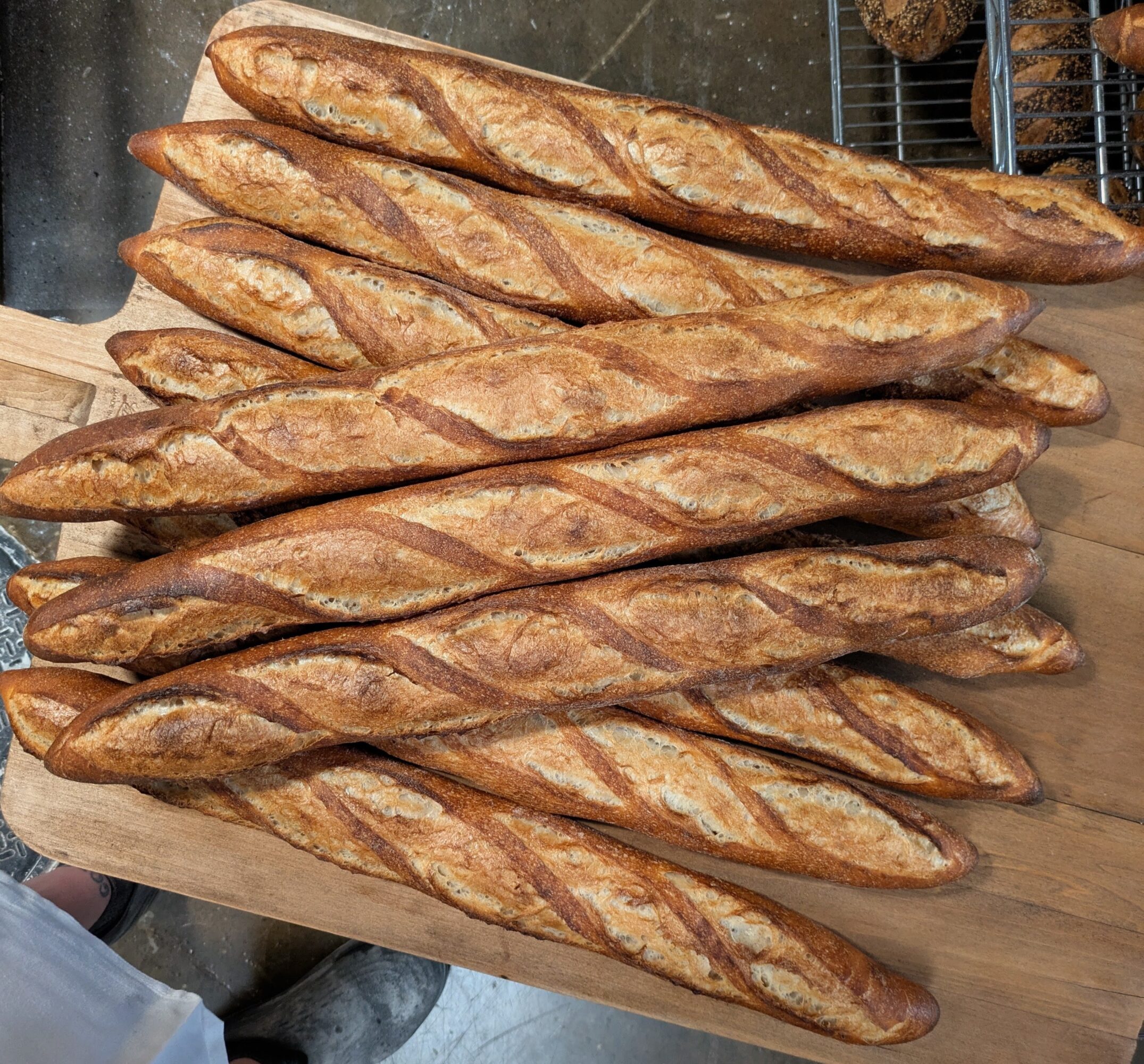 Multiple baguettes with golden crusts arranged on a wooden surface.