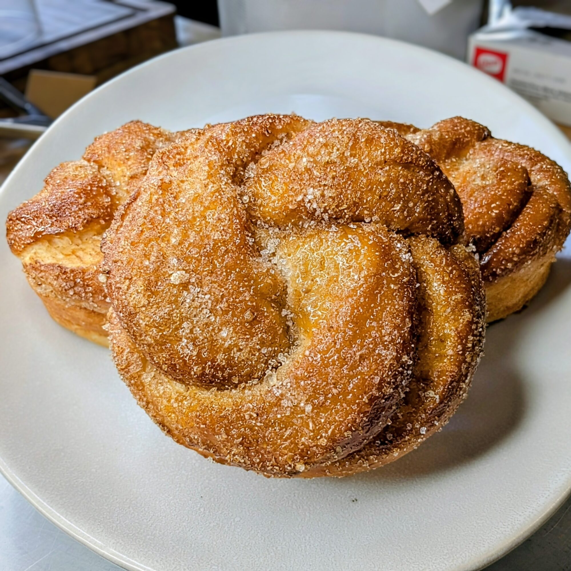 Three cinnamon sugar donuts on a white plate, with a blurred background.